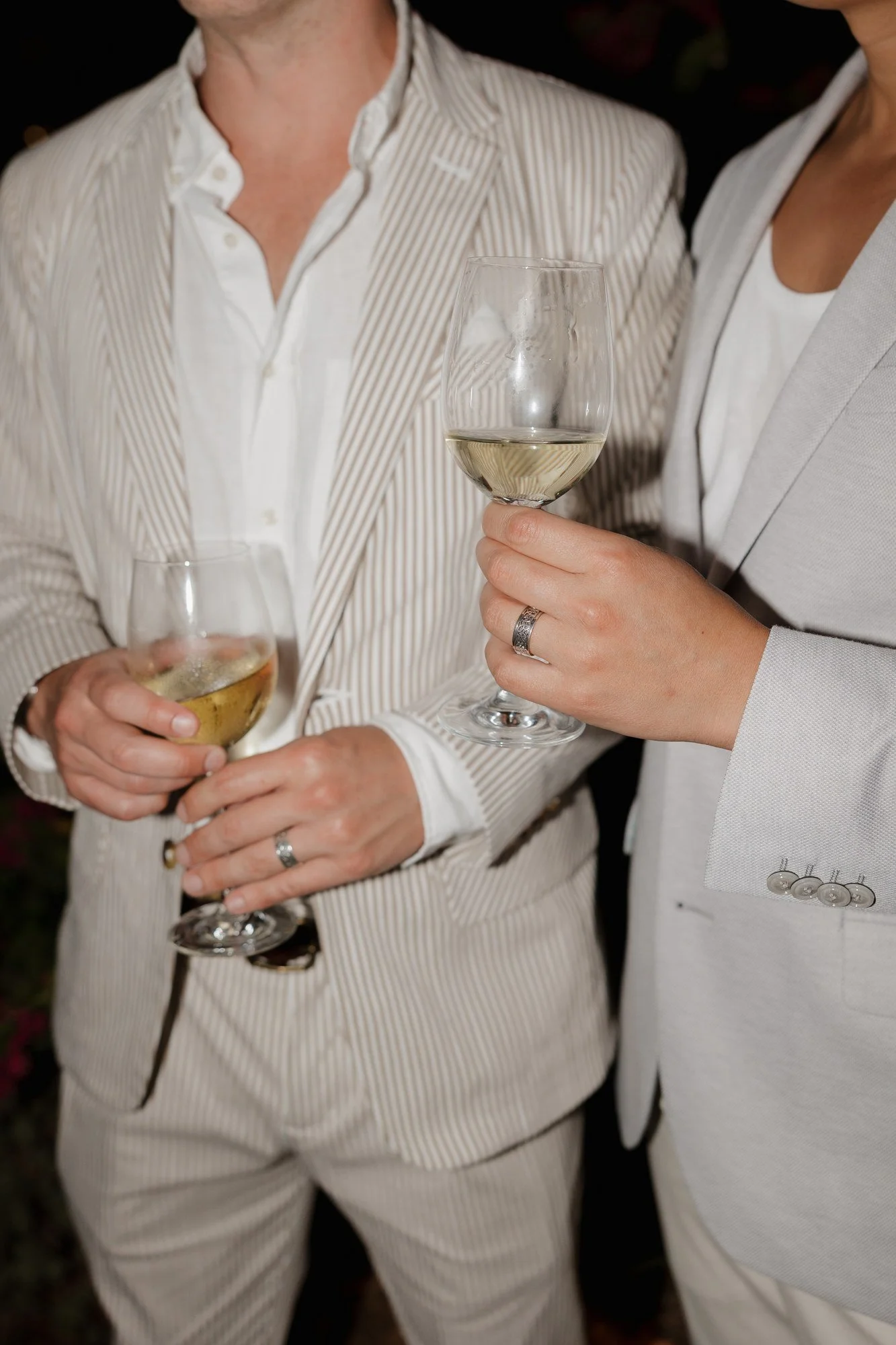 Close-up of Ryan and Sean holding glasses of white wine at their rehearsal dinner