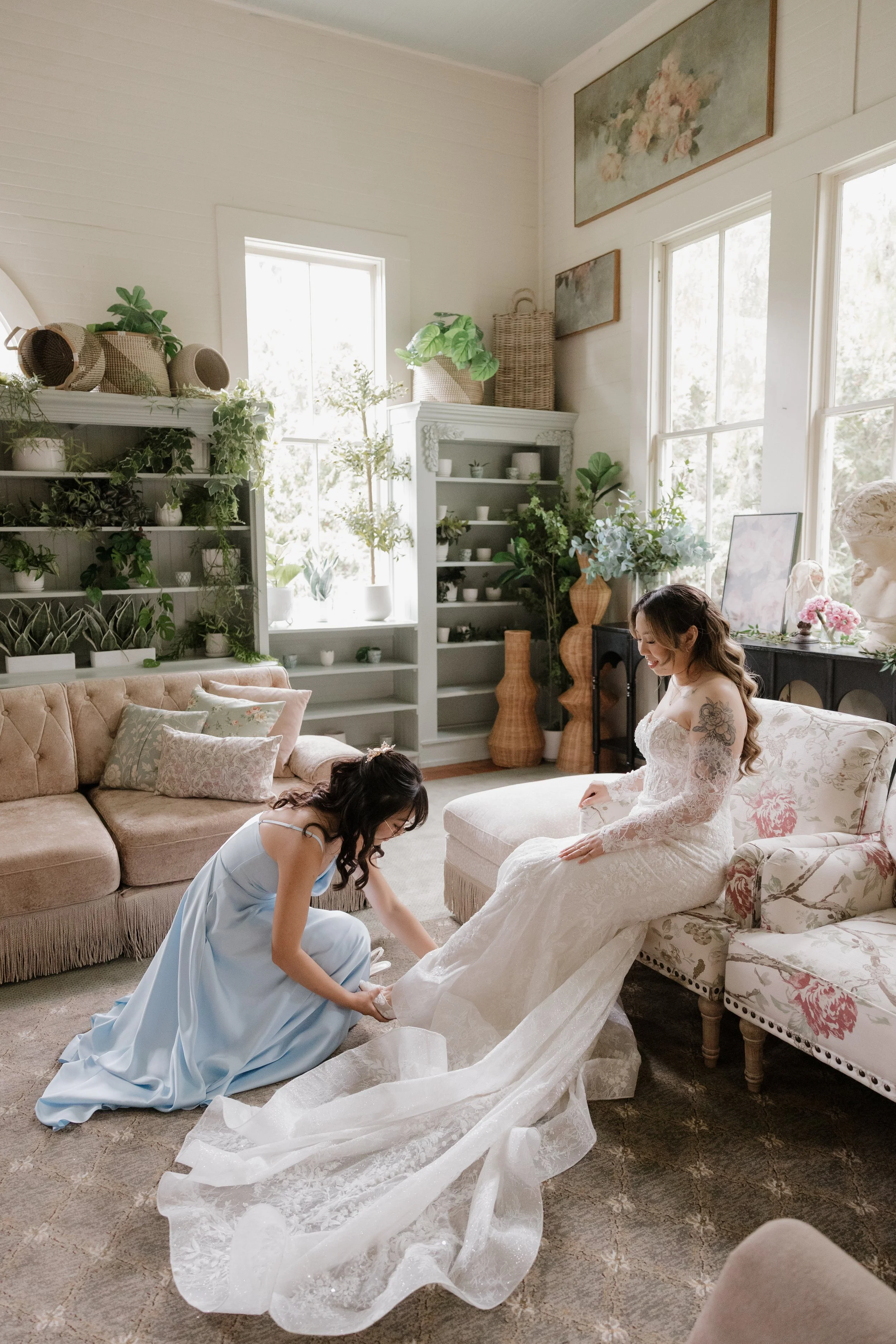 A bridesmaid fluffing Nancy's cathedral train in the Green Gables Bridal Salon