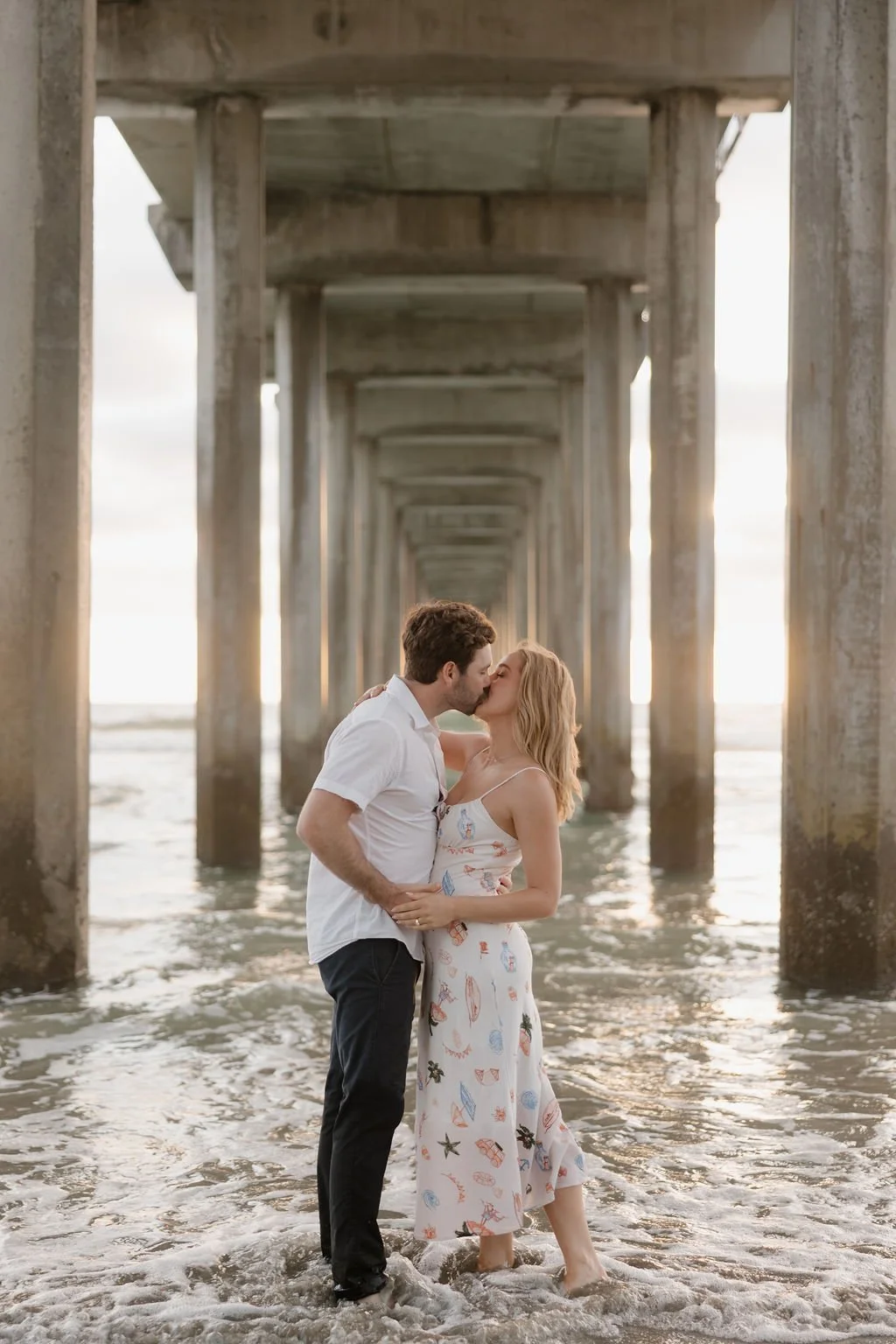 Couple kissing beneath the pilings of Scripps Pier in La Jolla