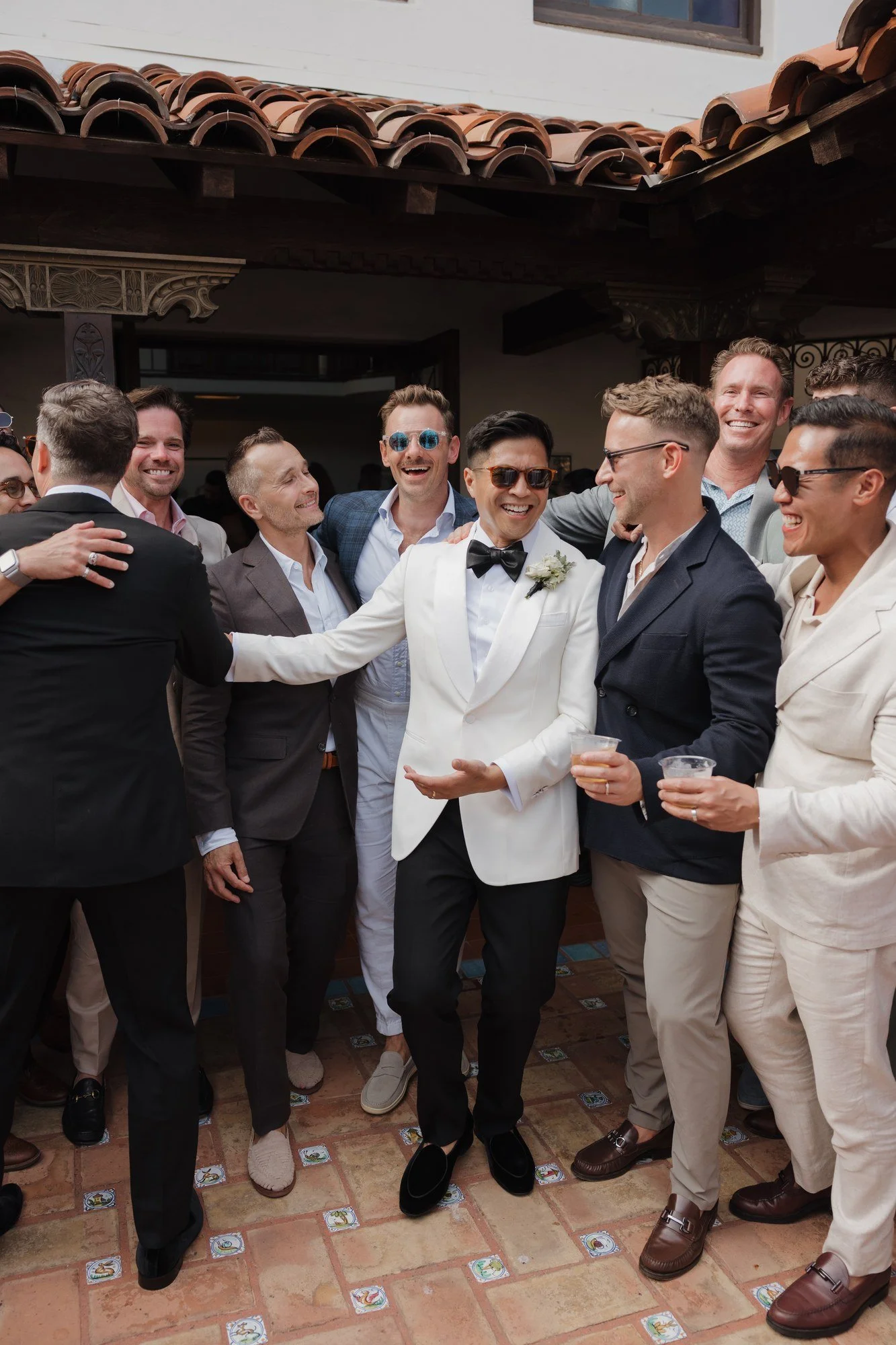 Ryan and Sean laughing and hugging friends during cocktail hour at Darlington House