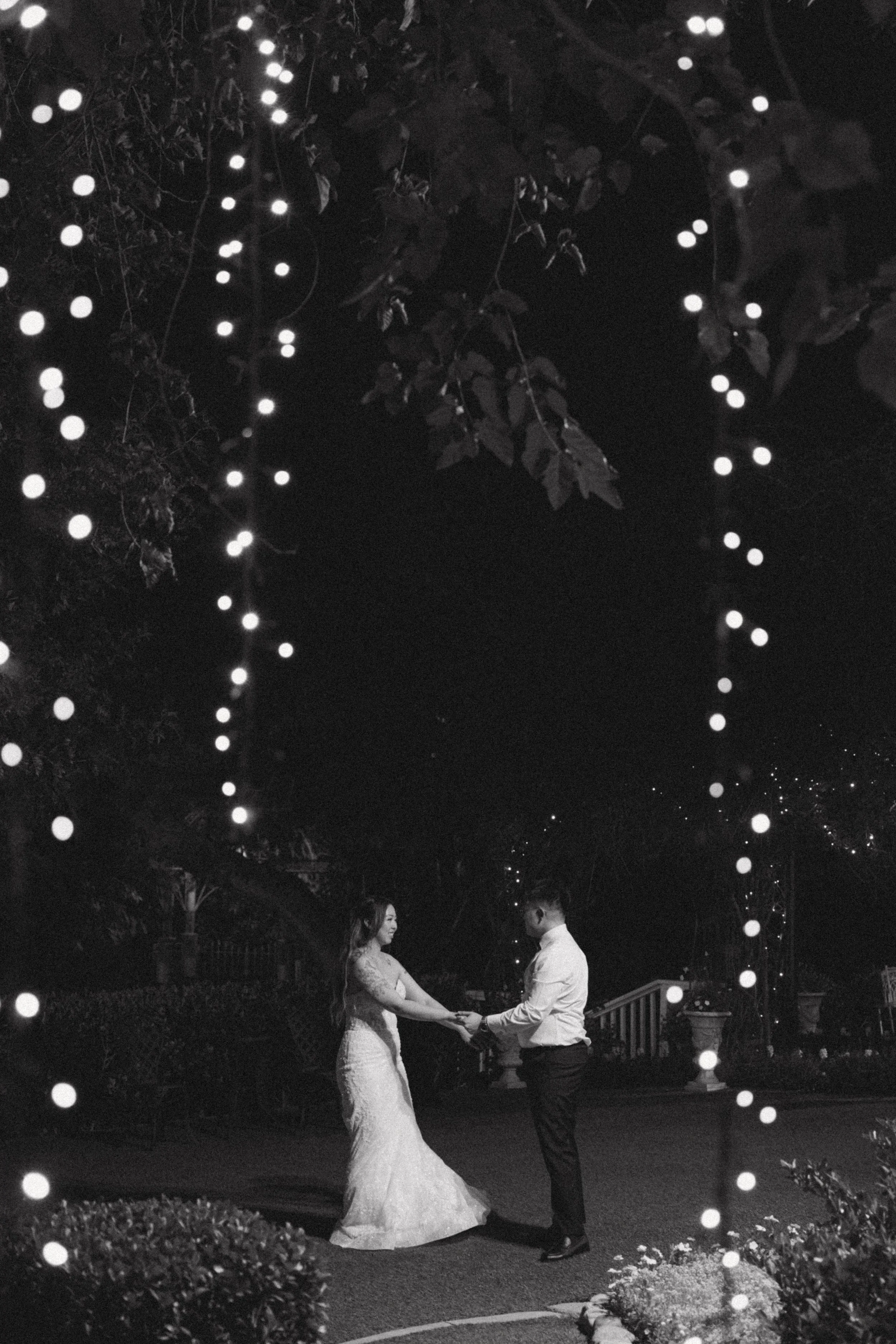 Black and white nighttime portrait of Nancy and Ken framed by twinkle lights at Green Gables
