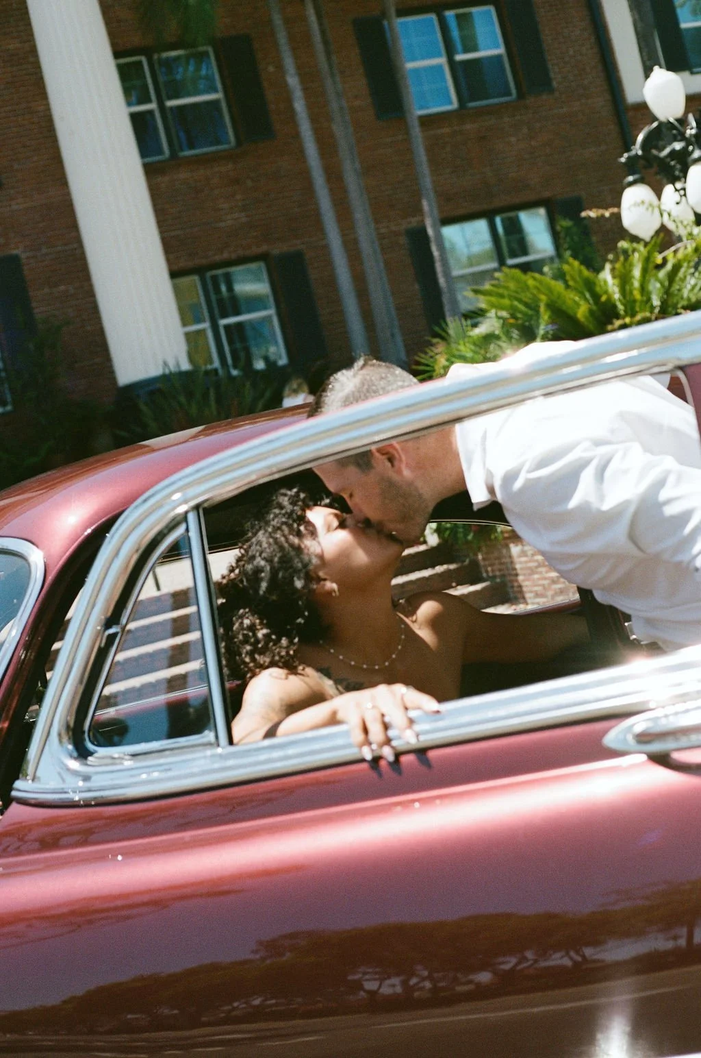 Candid kiss through the window of a vintage car outside the Lafayette Hotel