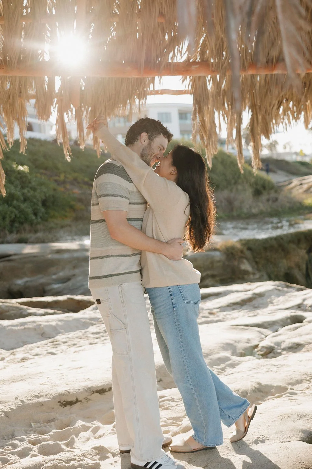Couple embracing under the historic palm-thatched shack at Windansea Beach