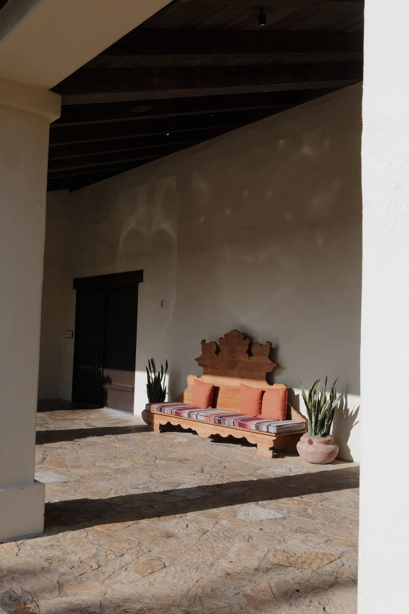 Shaded adobe veranda with a carved bench at Estancia La Jolla