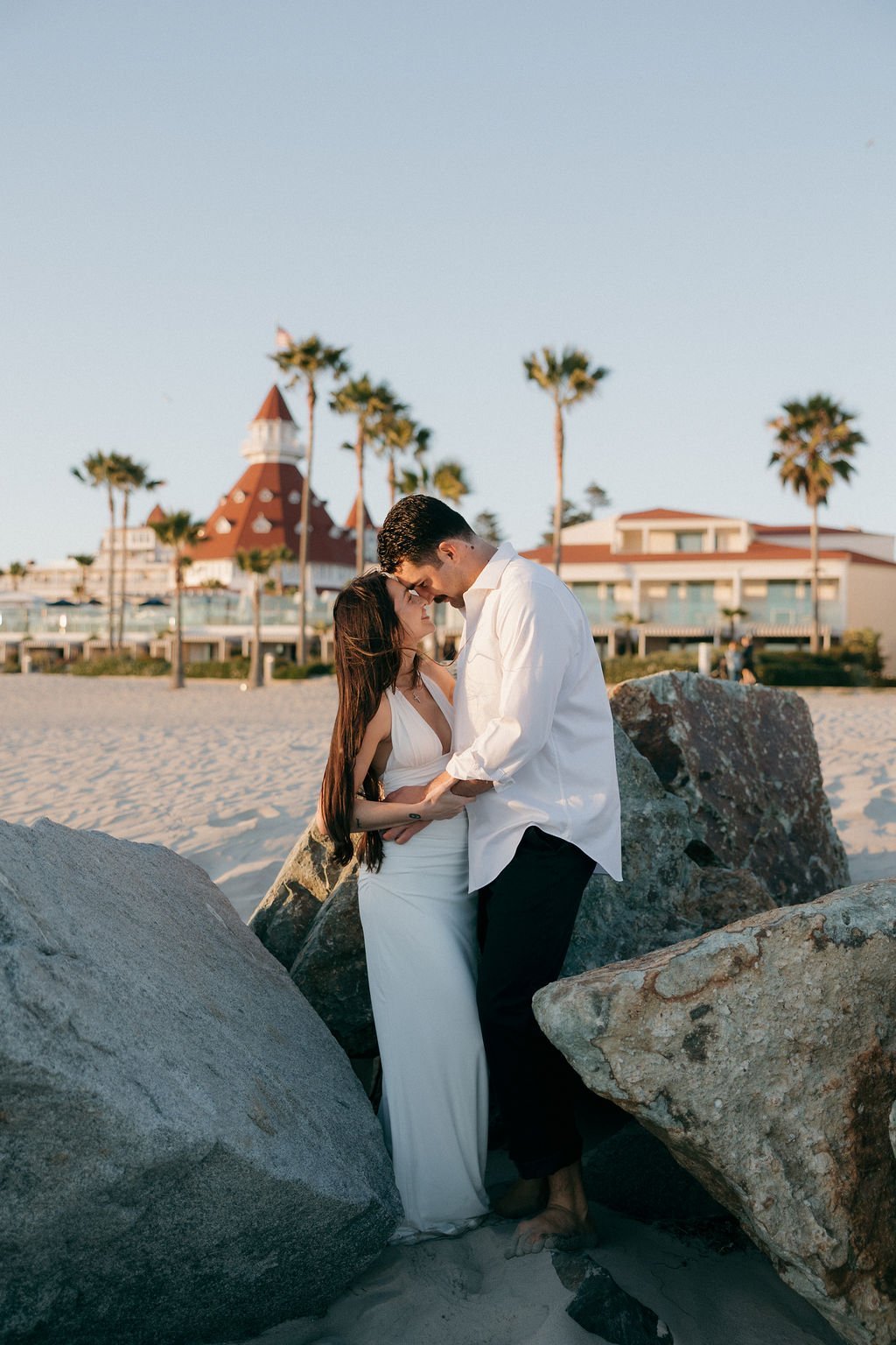 Couple kissing on the rocks with the Hotel del Coronado behind them