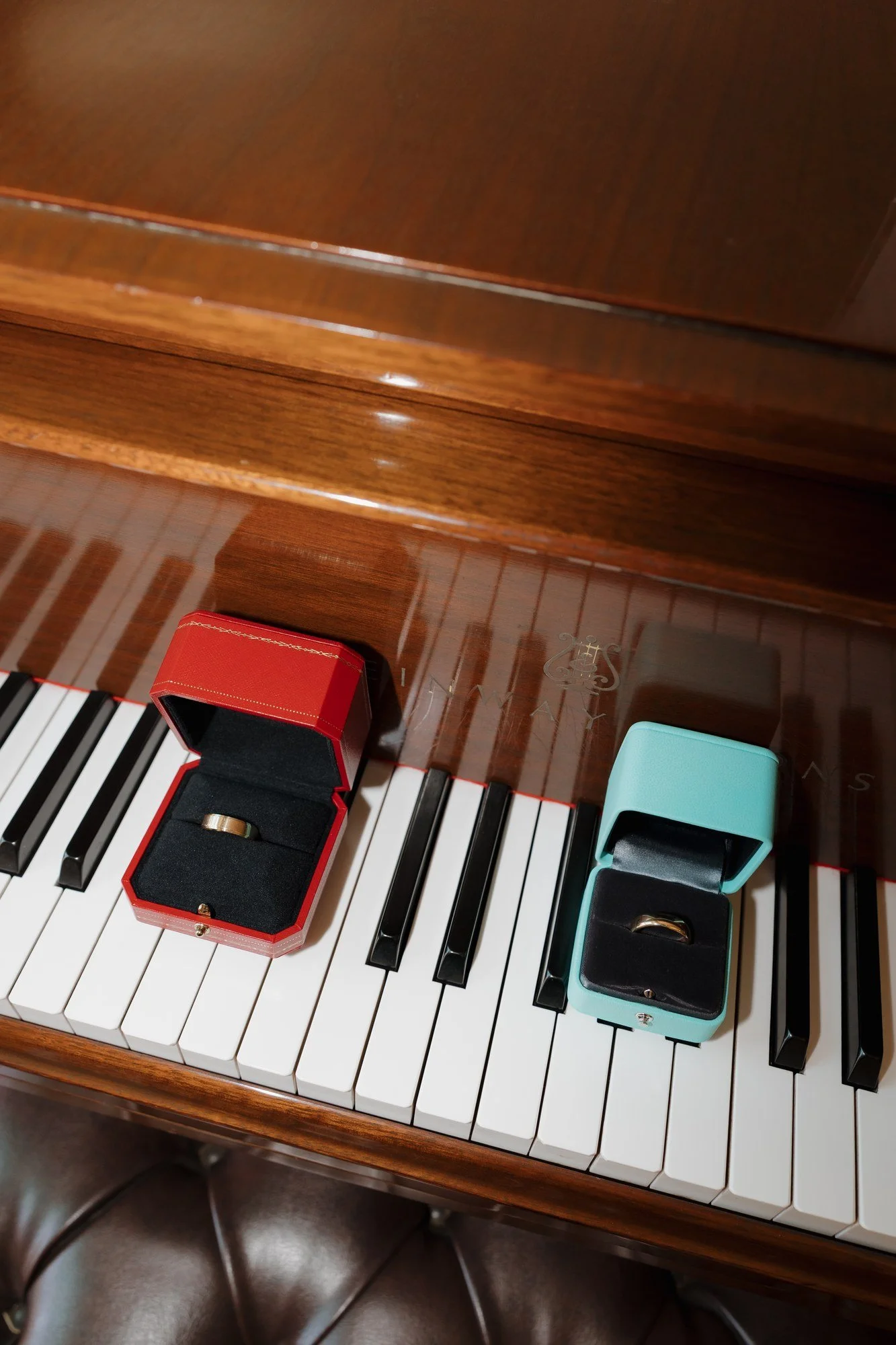 Two wedding bands in red and blue ring boxes resting on the piano keys at Darlington House