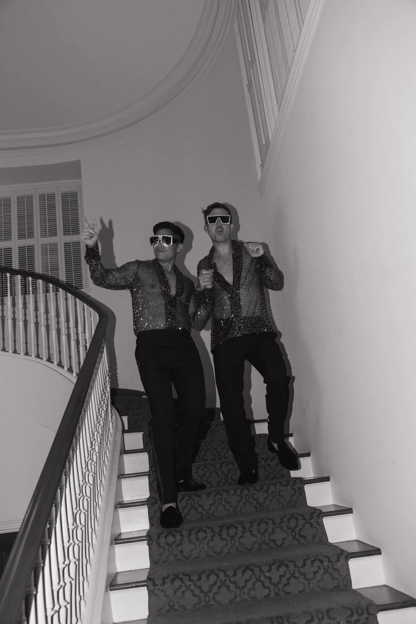 Black and white photo of Ryan and Sean posing on the staircase in their late-night outfits
