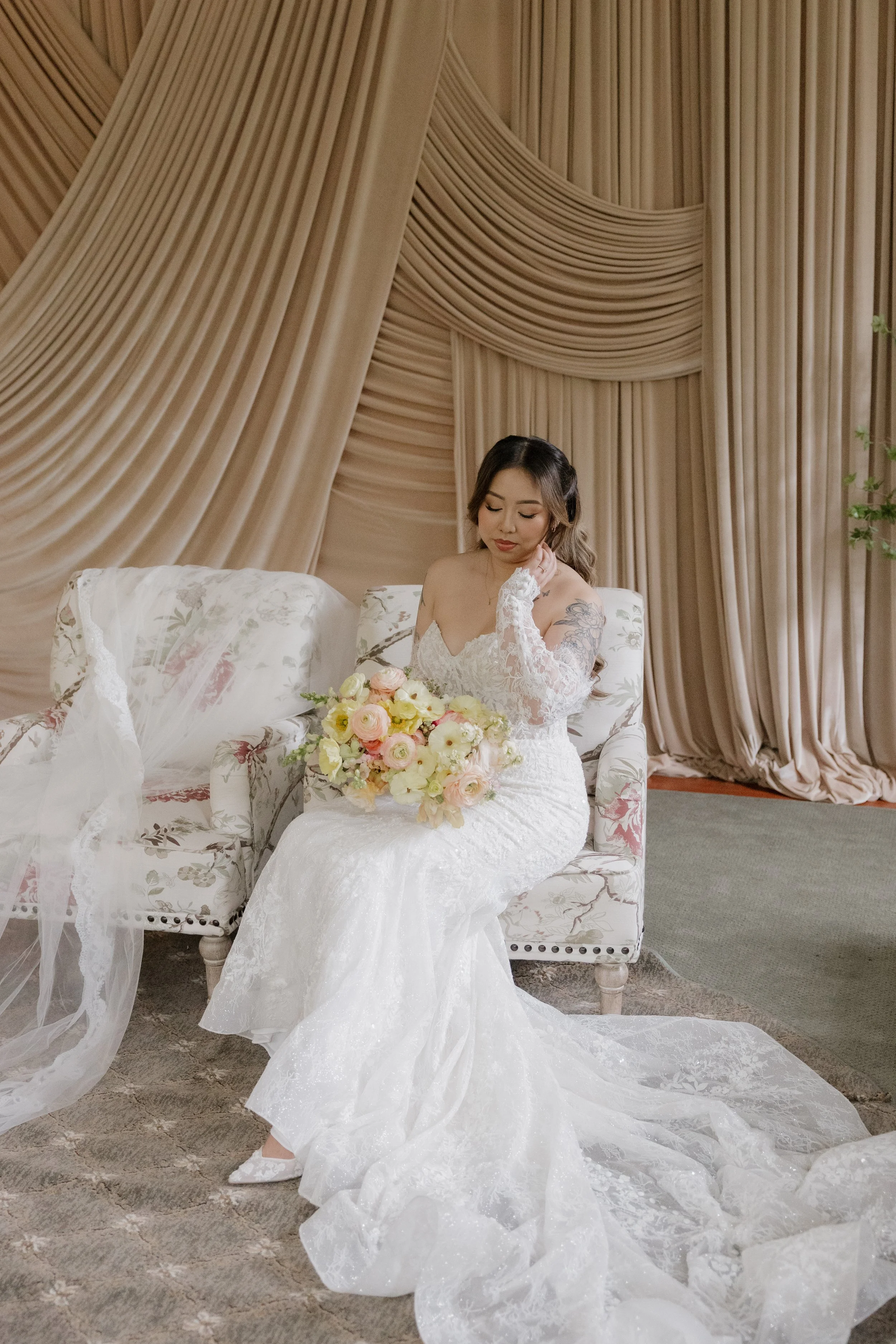 Nancy seated with her bouquet against draped fabric in the Green Gables Bridal Salon