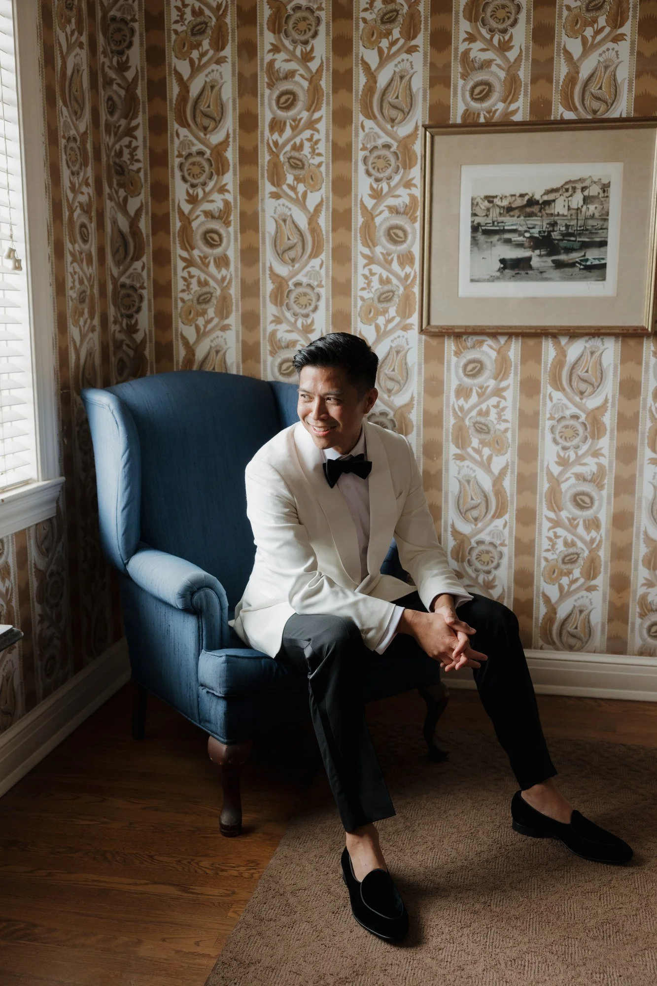 Ryan in his white tuxedo seated in a blue armchair at Darlington House
