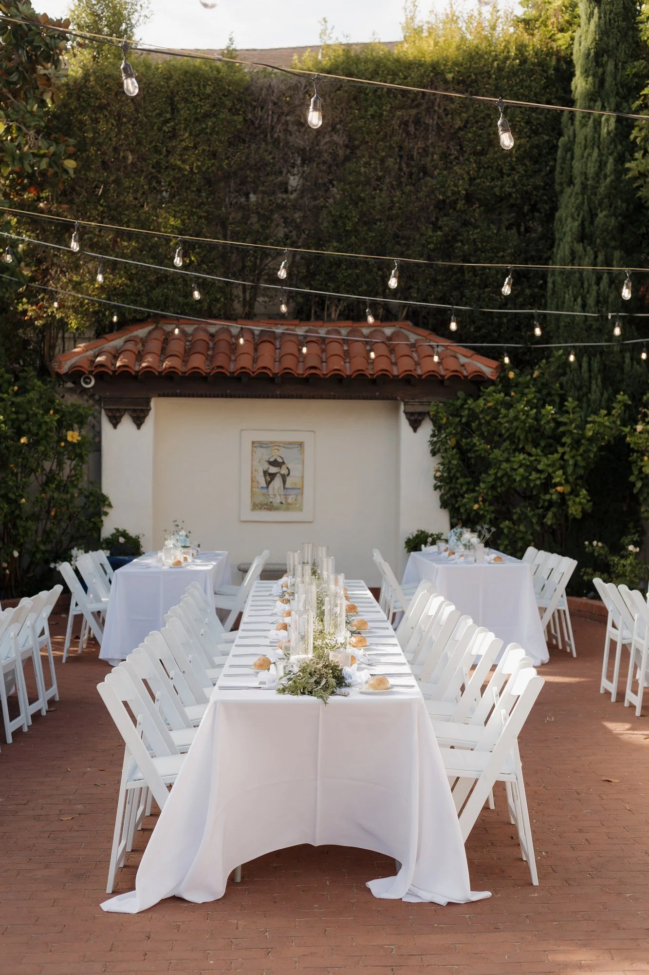 Reception tables with white linens beneath café lights at Darlington House