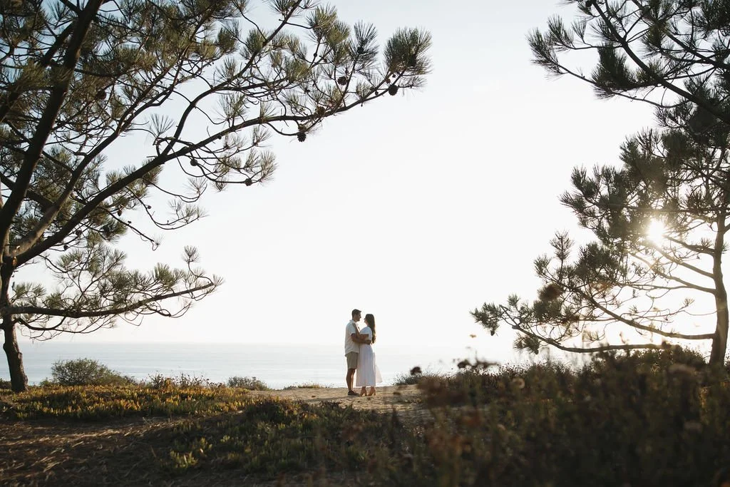 Couple framed by Torrey pine branches above the ocean at Torrey Pines