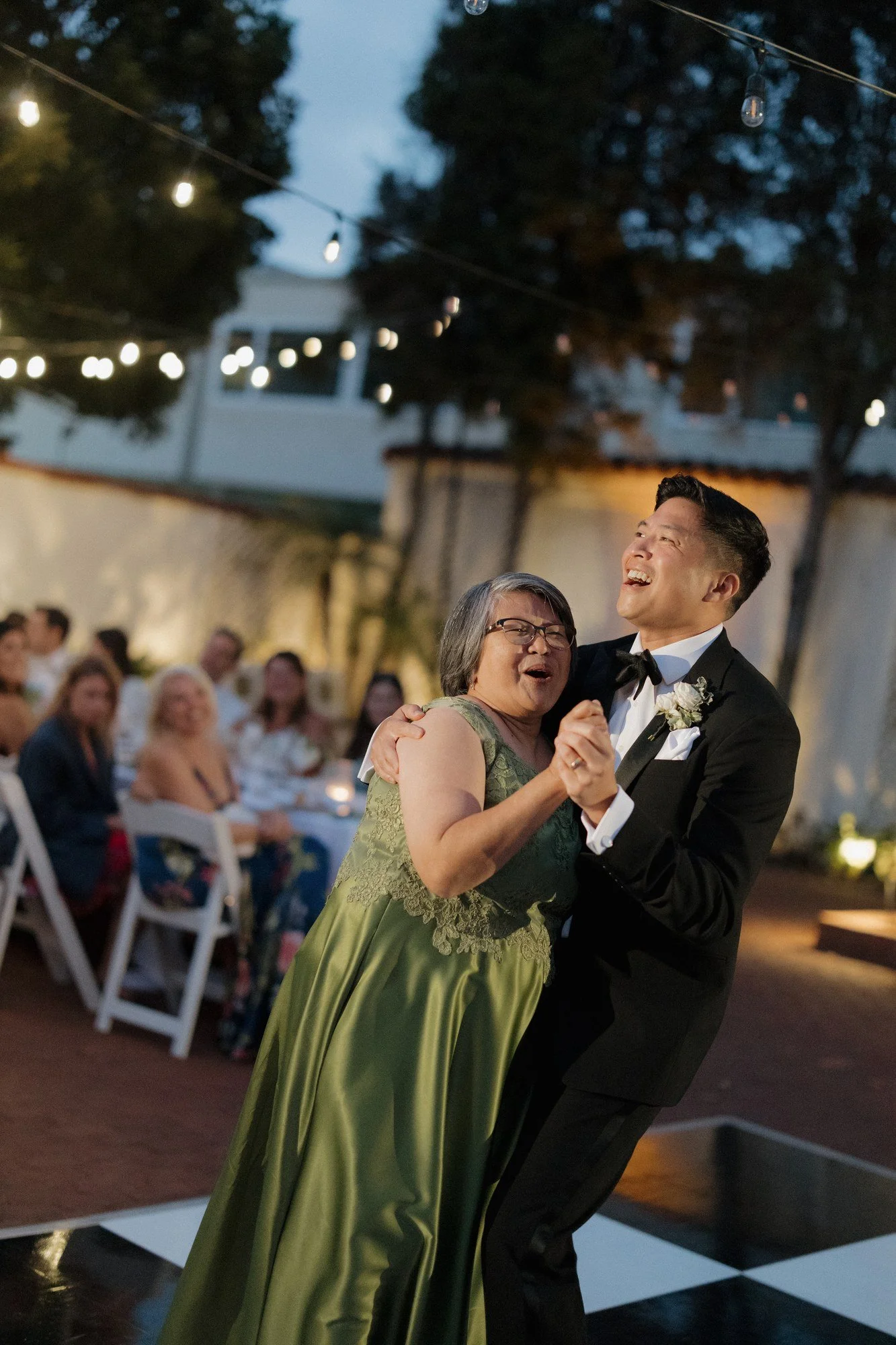 Groom sharing a mother-son dance under string lights at Darlington House