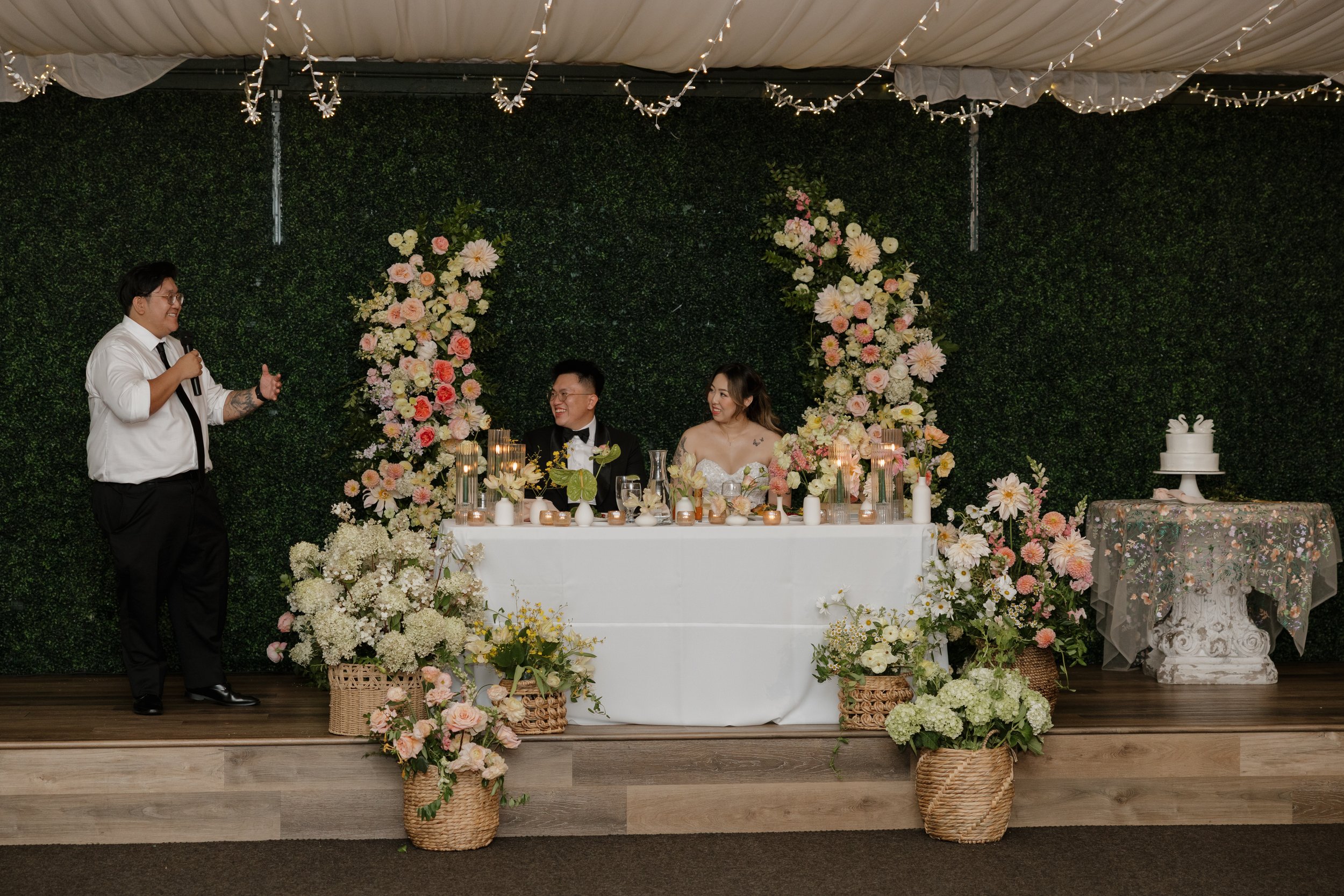 A wedding toast in front of Nancy and Ken's flower-filled sweetheart table at Green Gables