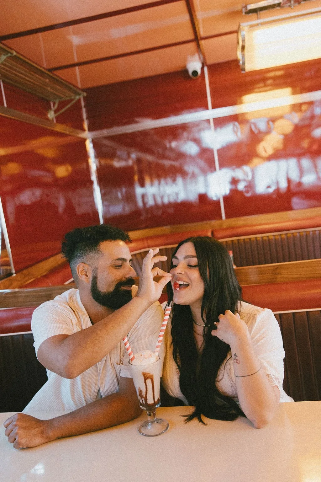 Playful moment sharing a milkshake in the Lafayette Hotel's retro diner