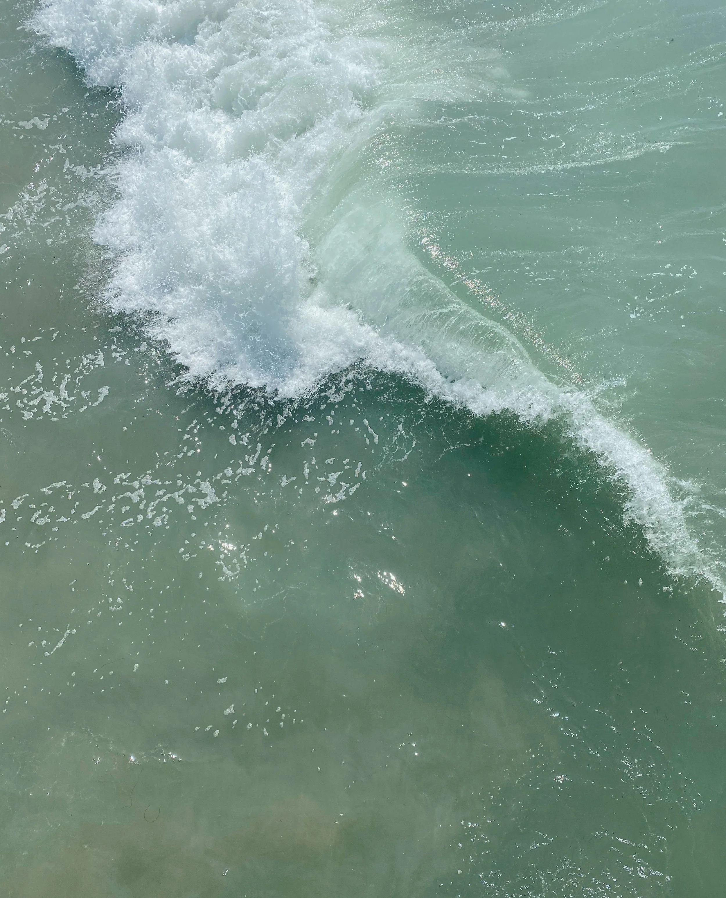 Close-up of ocean waves with white foam and clear green water.