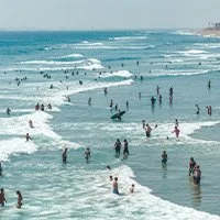People enjoying the beach and swimming in the ocean near the shoreline.