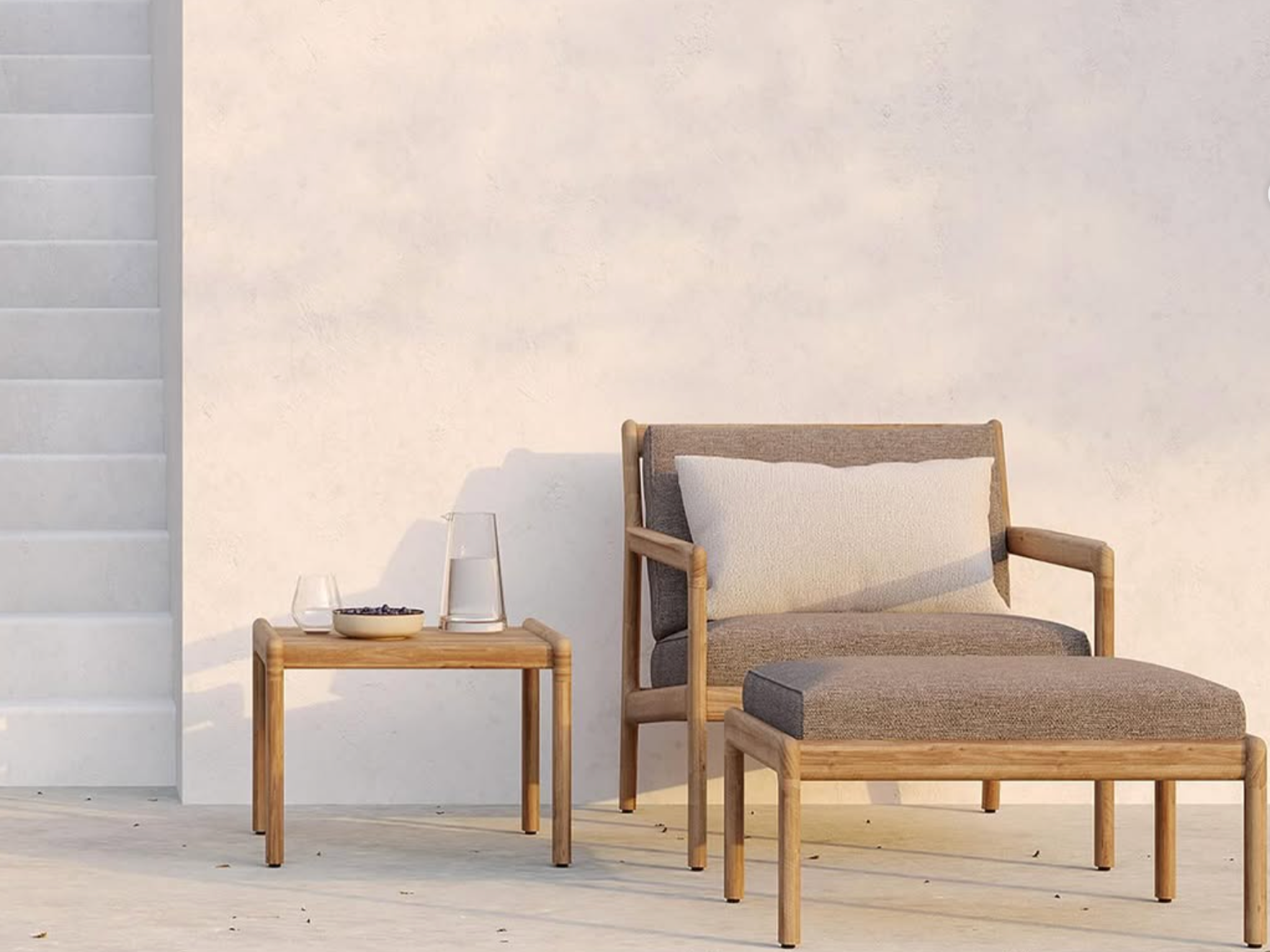 A minimalist outdoor patio with a wooden armchair with a cushion and a matching side table, against a white wall with stairs on the left.