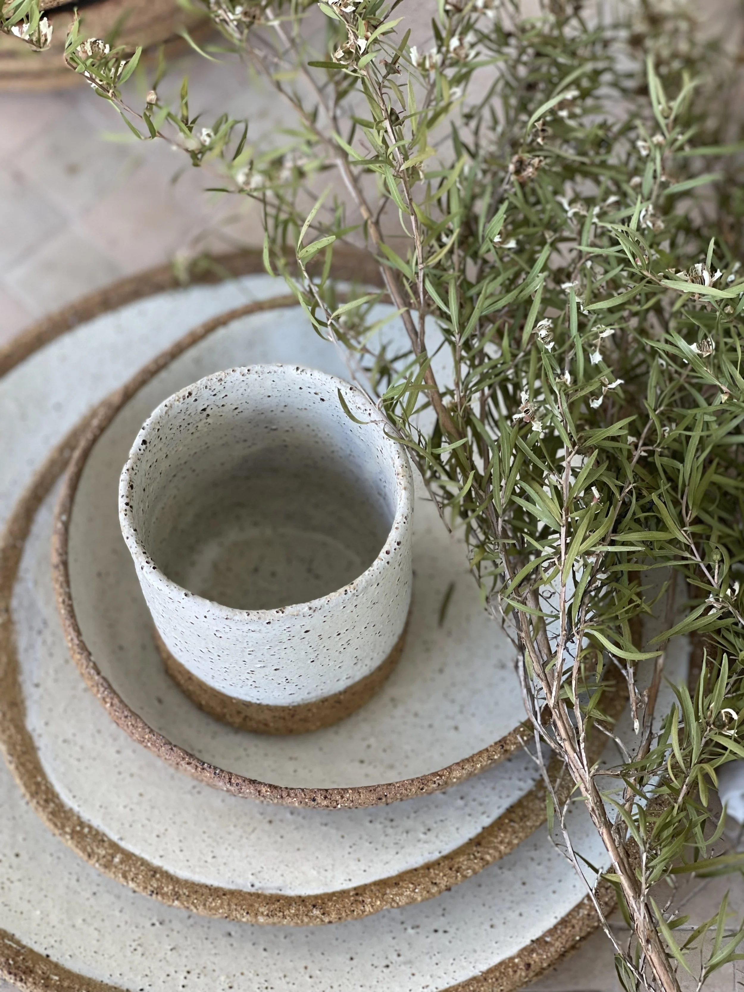 Stacked ceramic planters with a plant and greenery on the side.