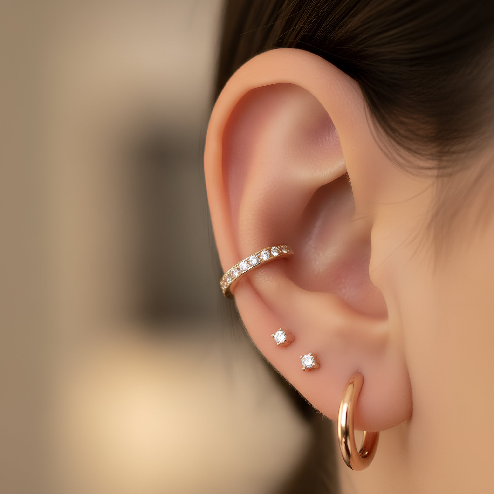 Minimal ear piercing with gold hoop and stud earrings, featuring cartilage and lobe piercings with a clean aesthetic