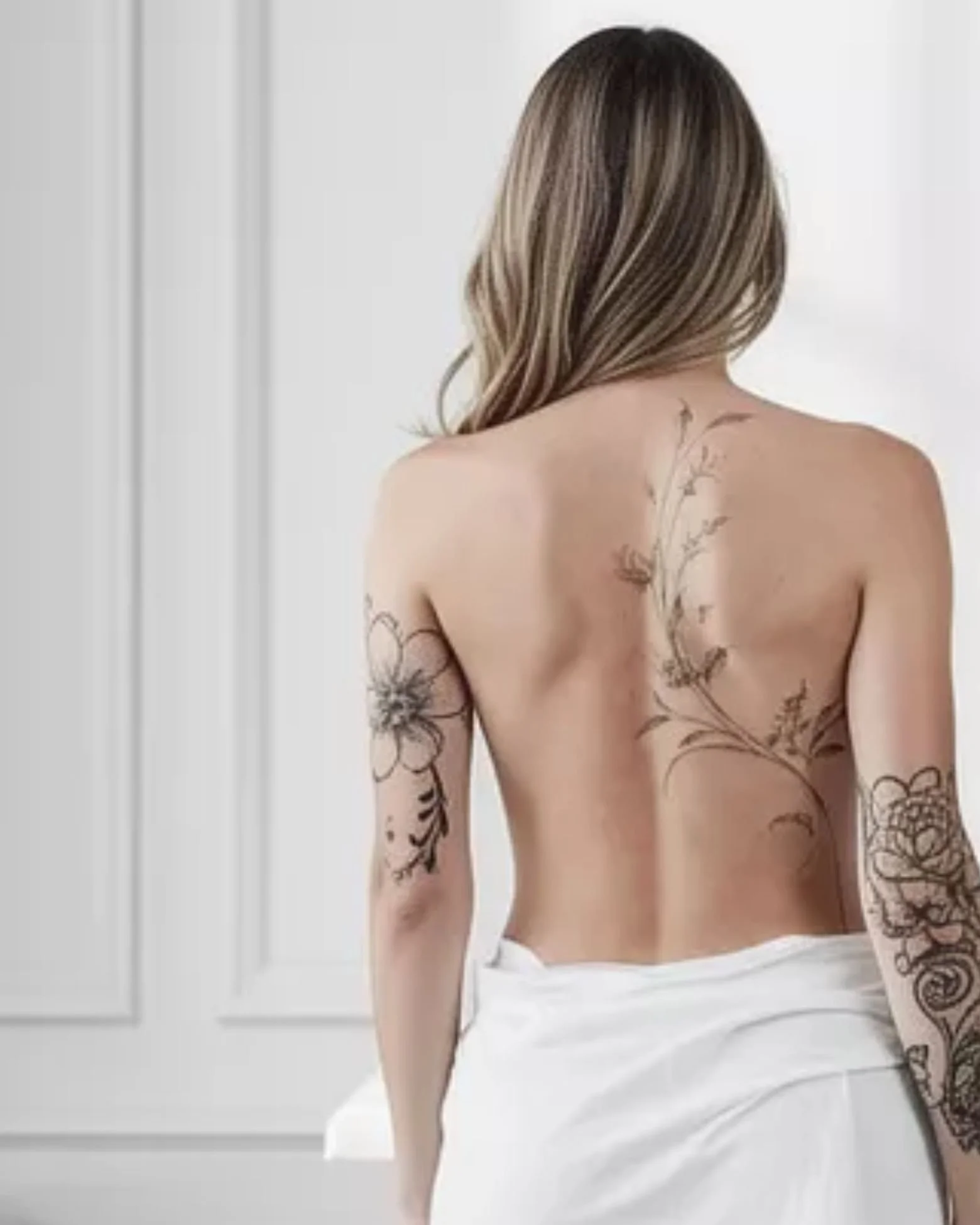 Fine line floral back and leg tattoos with minimalist design by Salvation Beauty Ink