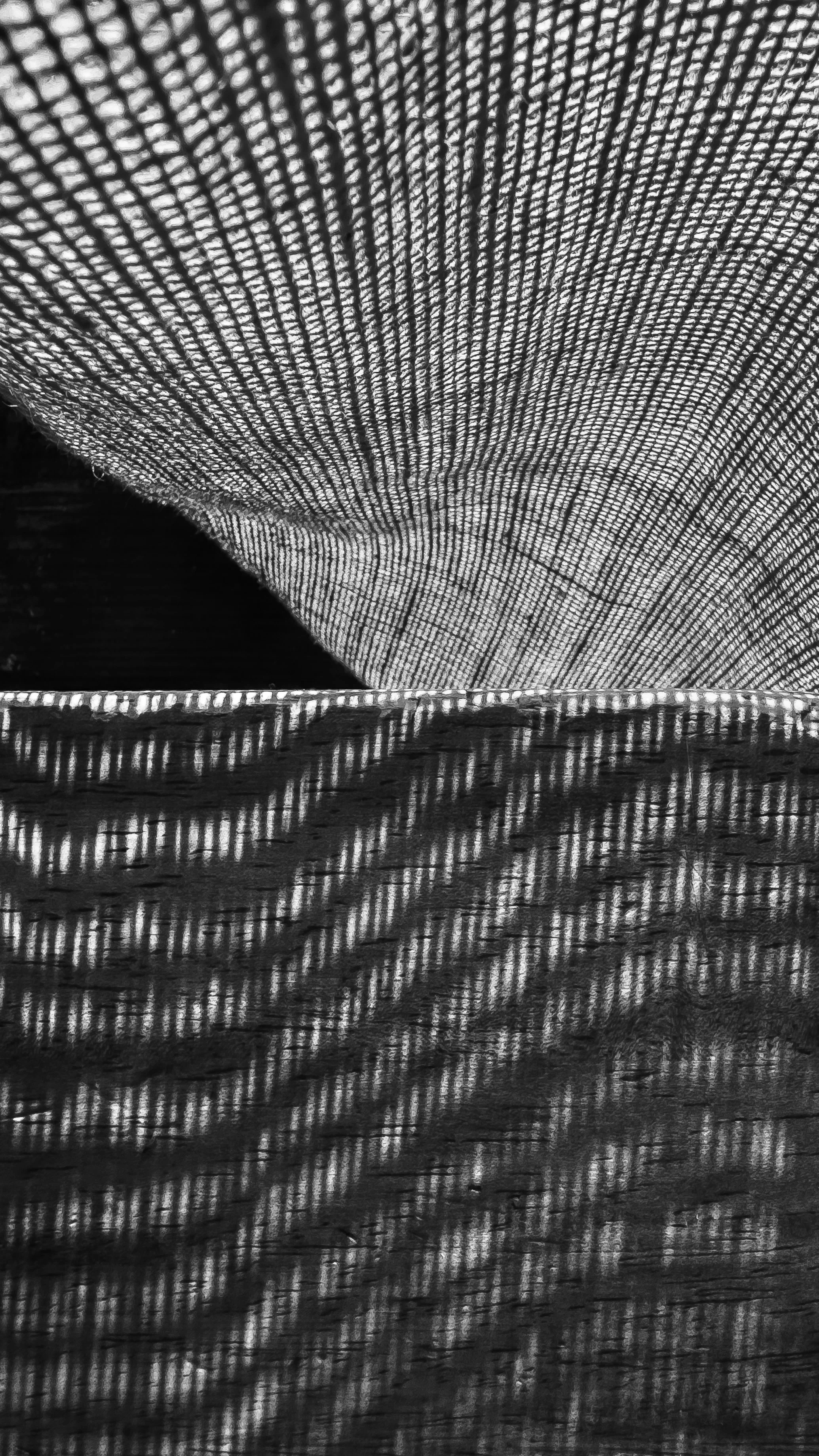 Superposición de sombras y luz a través de una tela de malla negra con patrones geométricos, en un entorno oscuro.