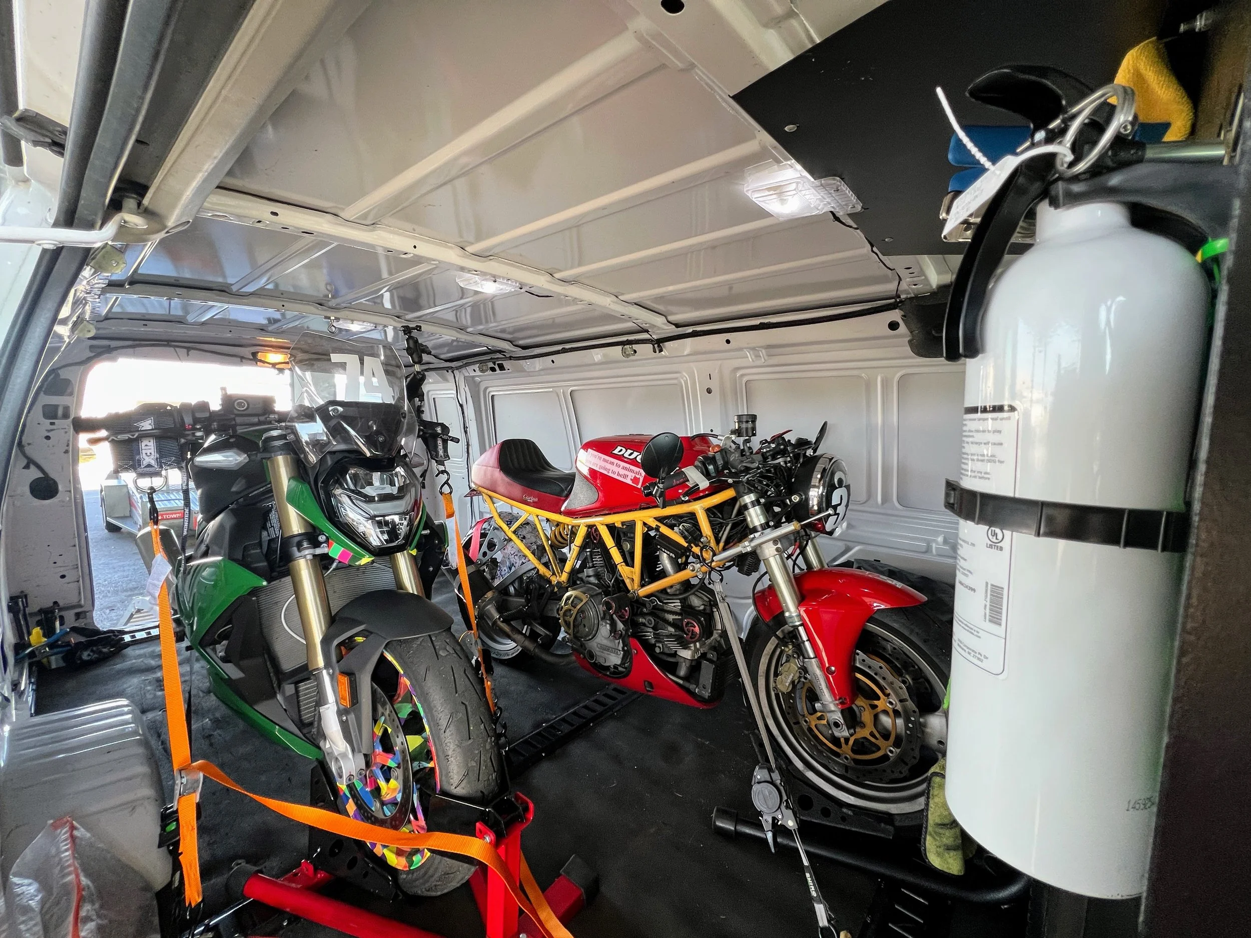 The inside of the cargo van of 31 cats, with 2 motorcycles inside, safety secured, going to a race track