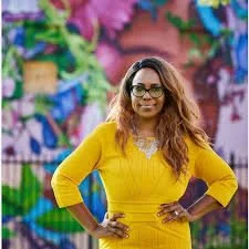 Woman in yellow dress standing in front of colorful graffiti wall