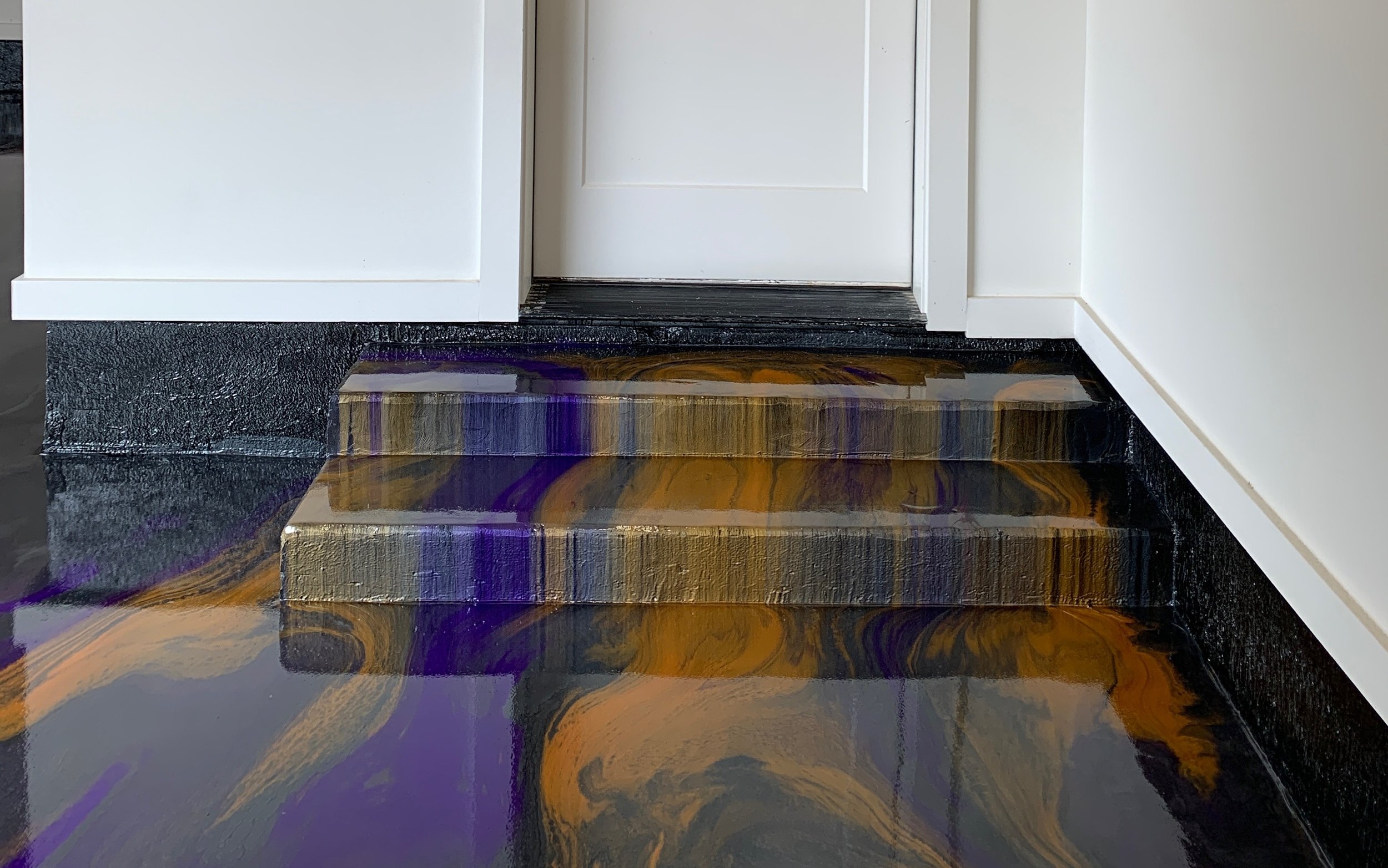 Interior view of a white door with steps below it, featuring an epoxy slate, purple, and gold swirled marble-patterned floor.