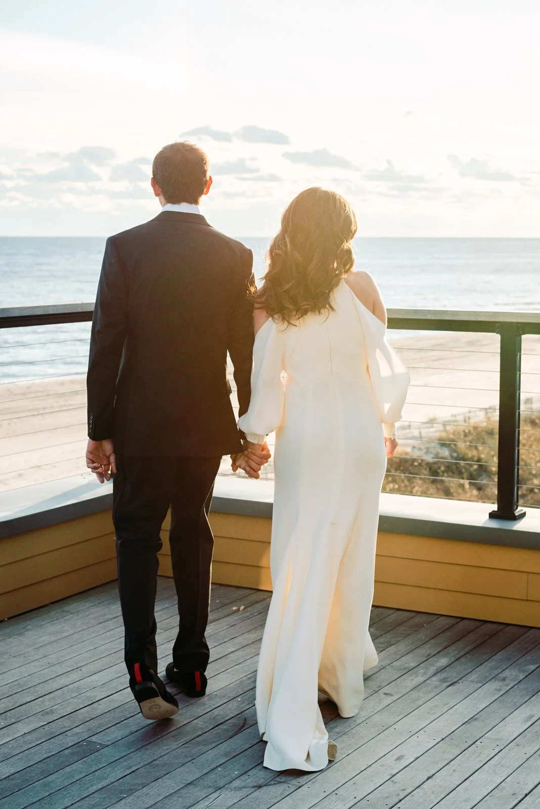 Bride and groom looking out at the ocean at golden hour during their winter wedding at Gurney's Montauk