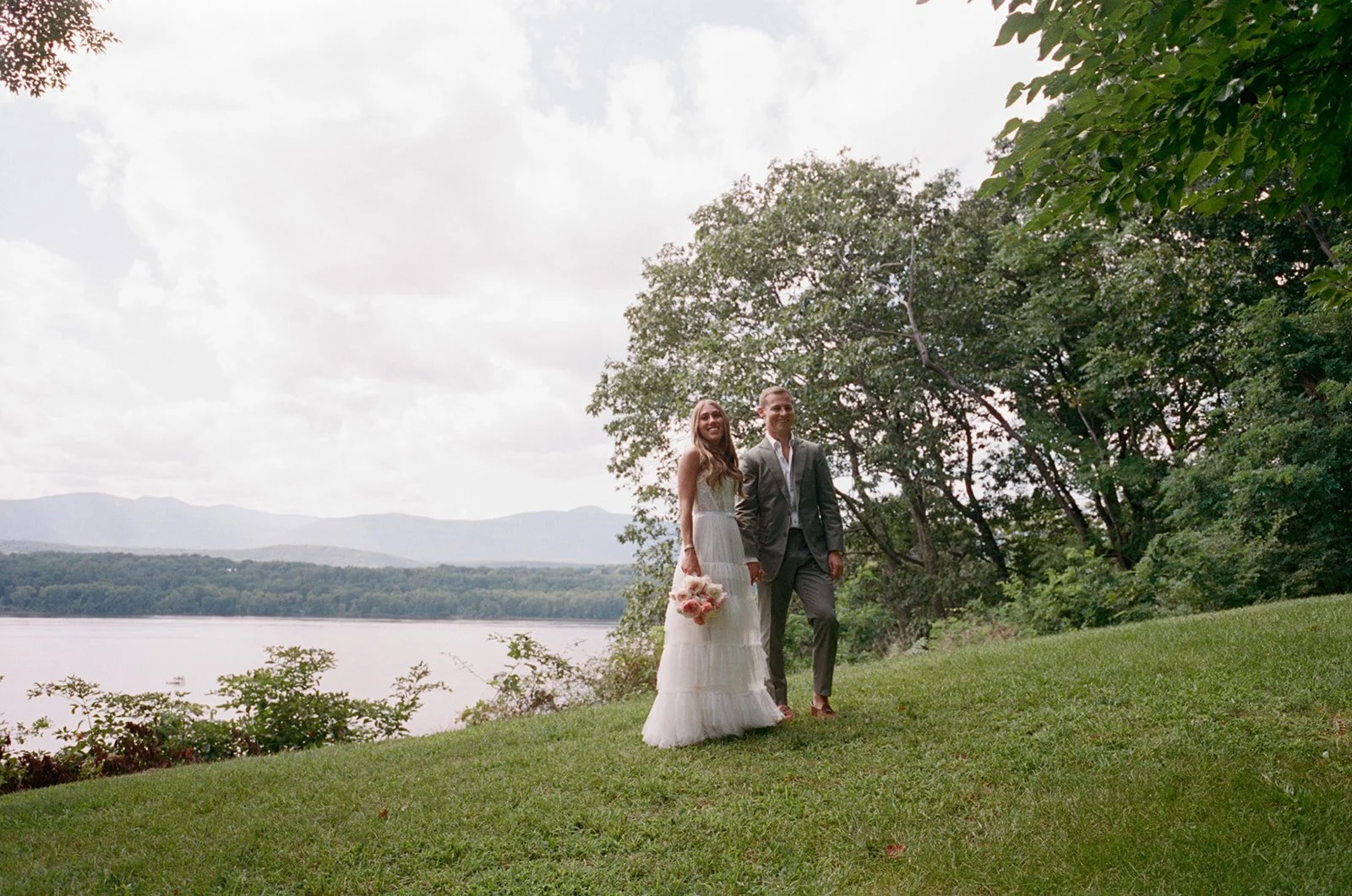 Bride and groom on a hilltop above the Hudson River and the Catskill Mountains at Southwood Estate in Germantown, NY