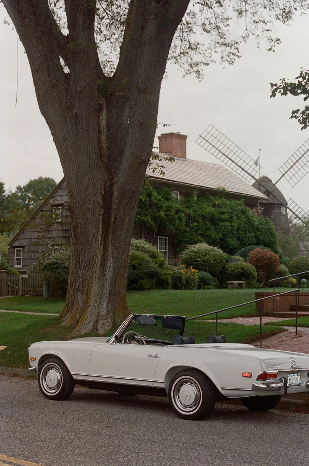 Vintage convertible parked under an old tree by the James Lane windmill in East Hampton