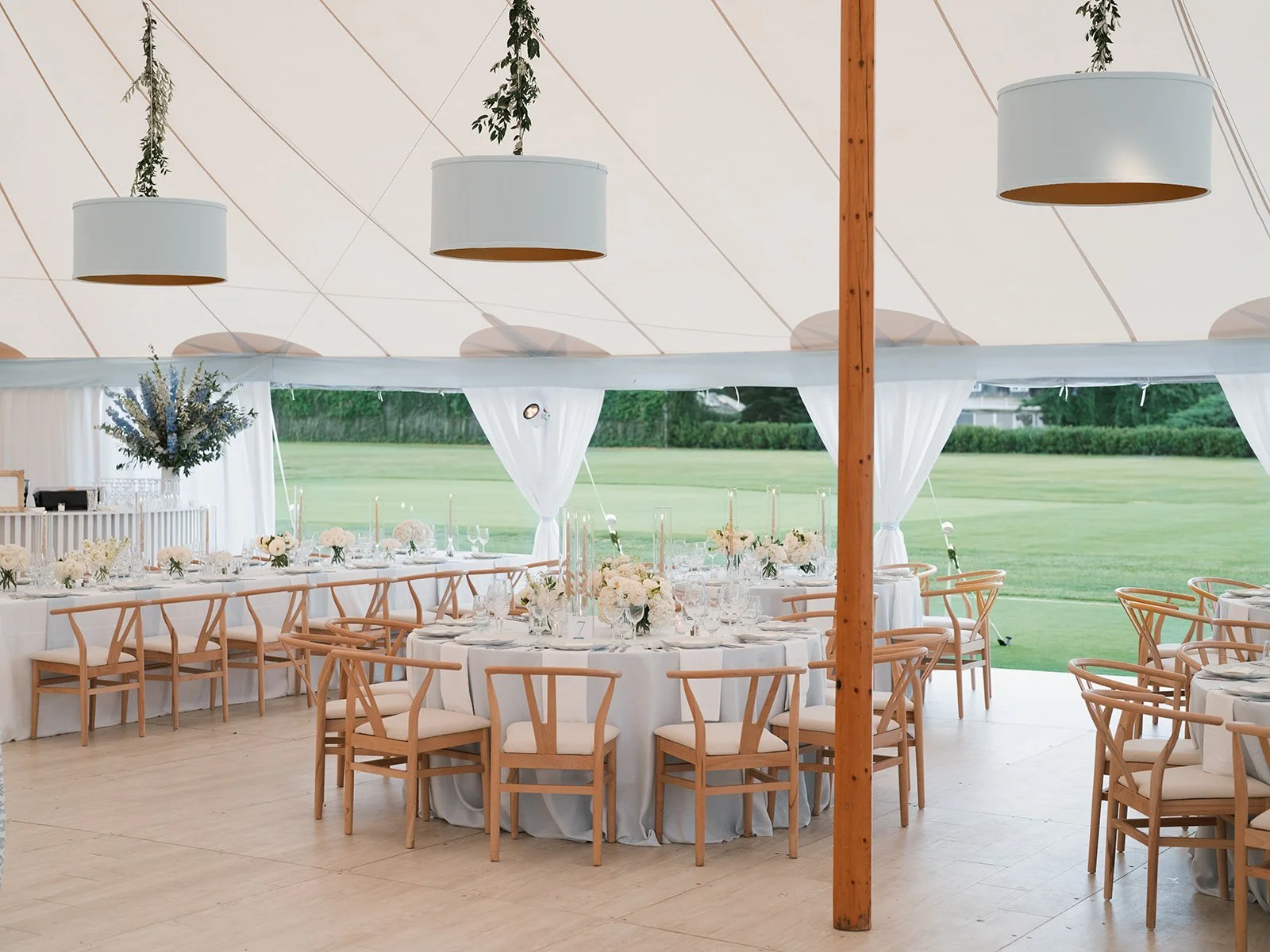 Sailcloth tent with round tables and wishbone chairs set for the reception at The Maidstone Club
