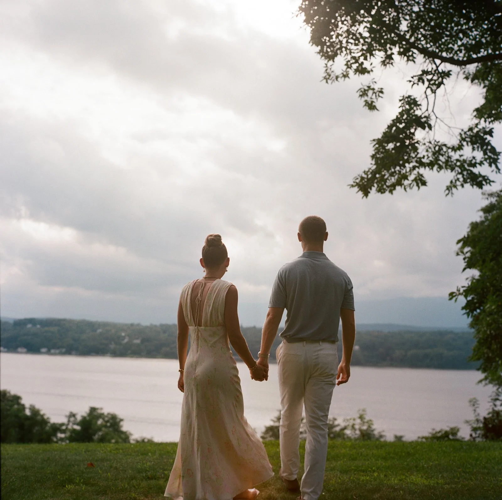 Couple walking hand in hand toward the Hudson River during their welcome dinner at Southwood Estate in Germantown, NY