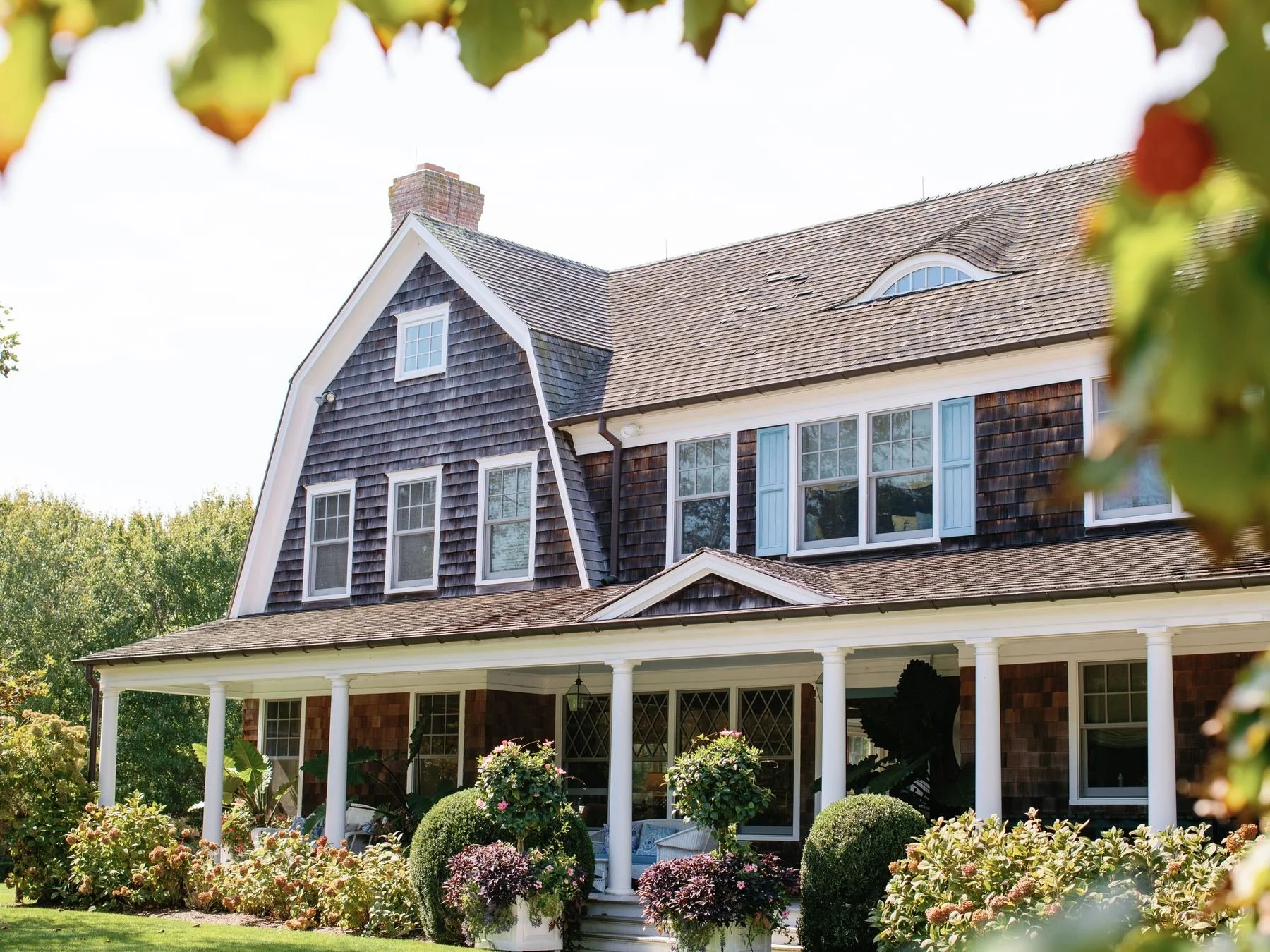 Shingled house with a wide porch and flower beds in East Hampton