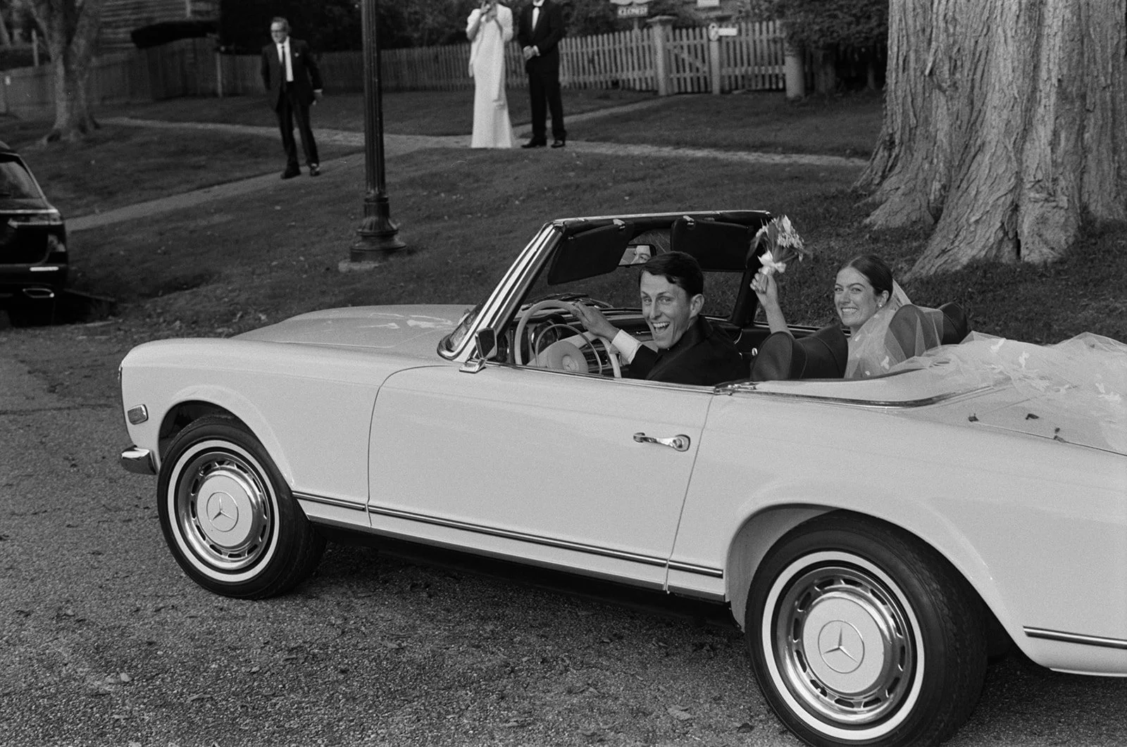 Black and white photo of the newlyweds driving away in the convertible in East Hampton