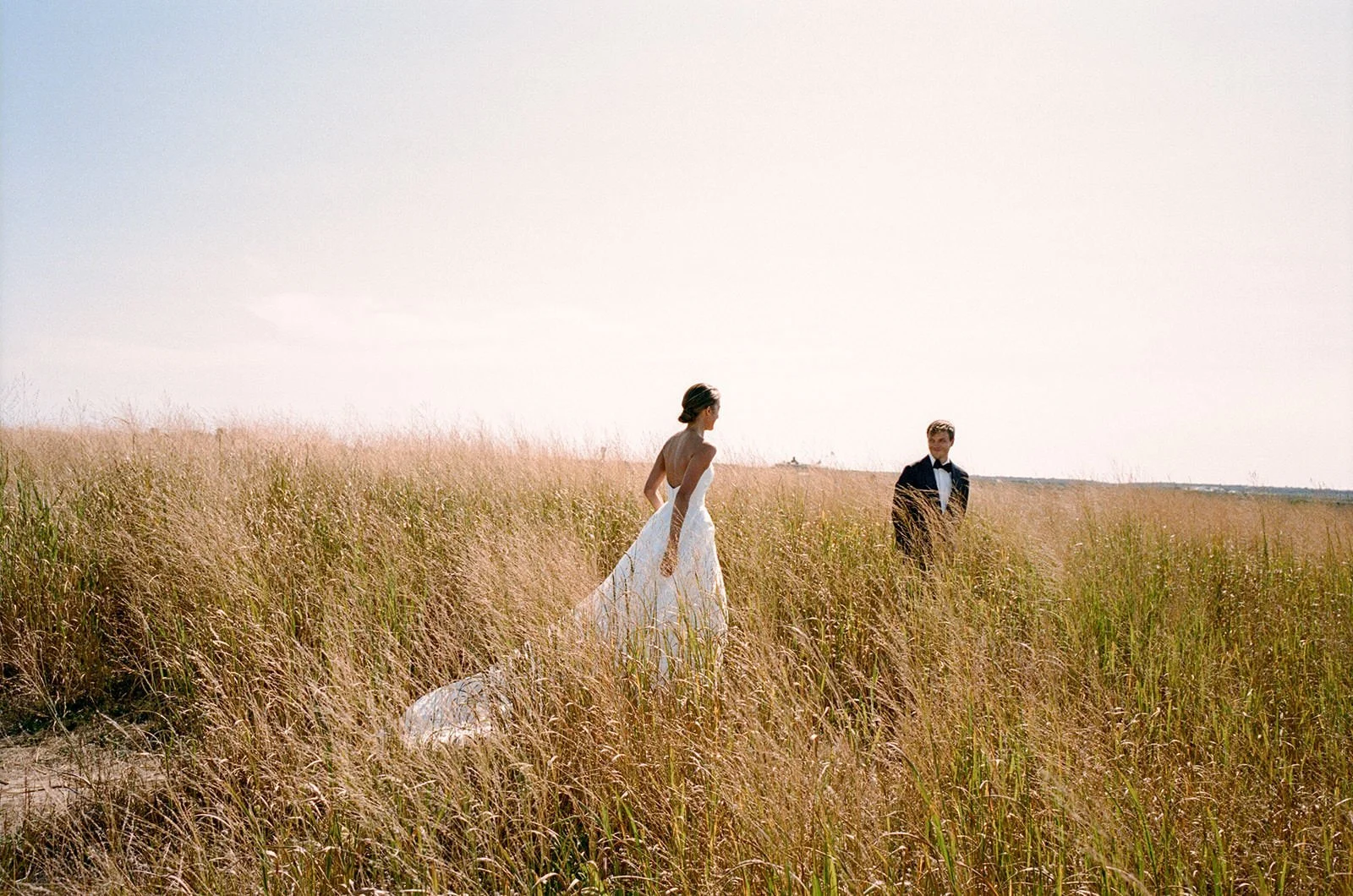 Bride walking through tall golden grass toward the groom on Nantucket