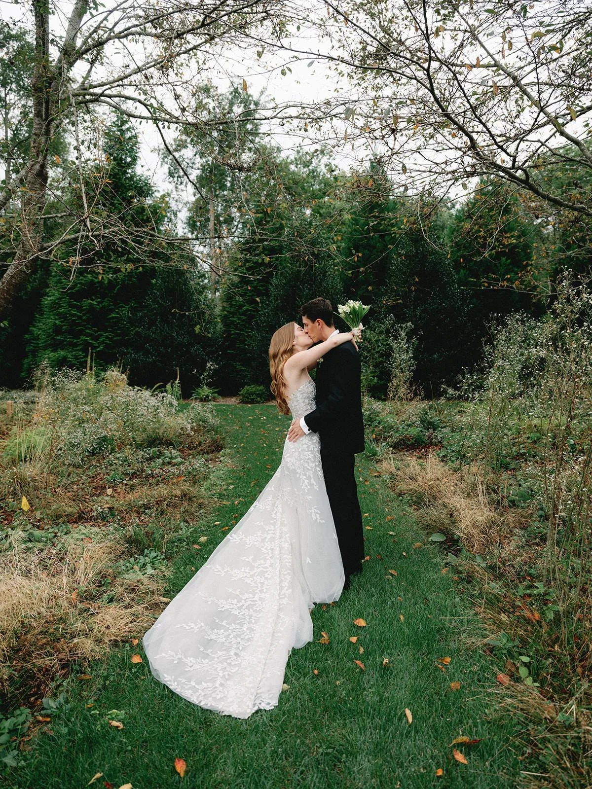 Bride and groom embracing in the tall grass at her family home in East Hampton