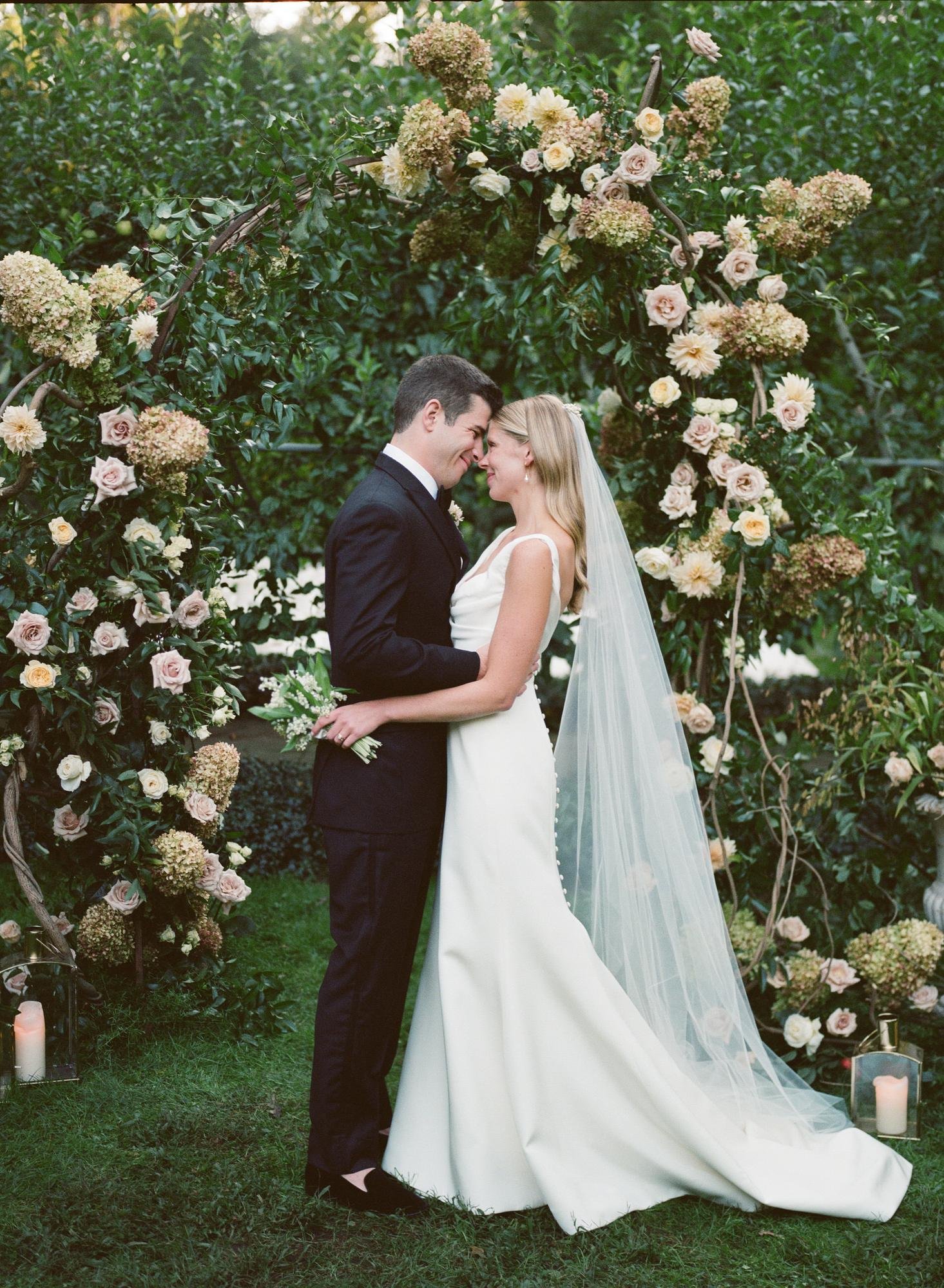 Couple forehead to forehead beside climbing roses in East Hampton