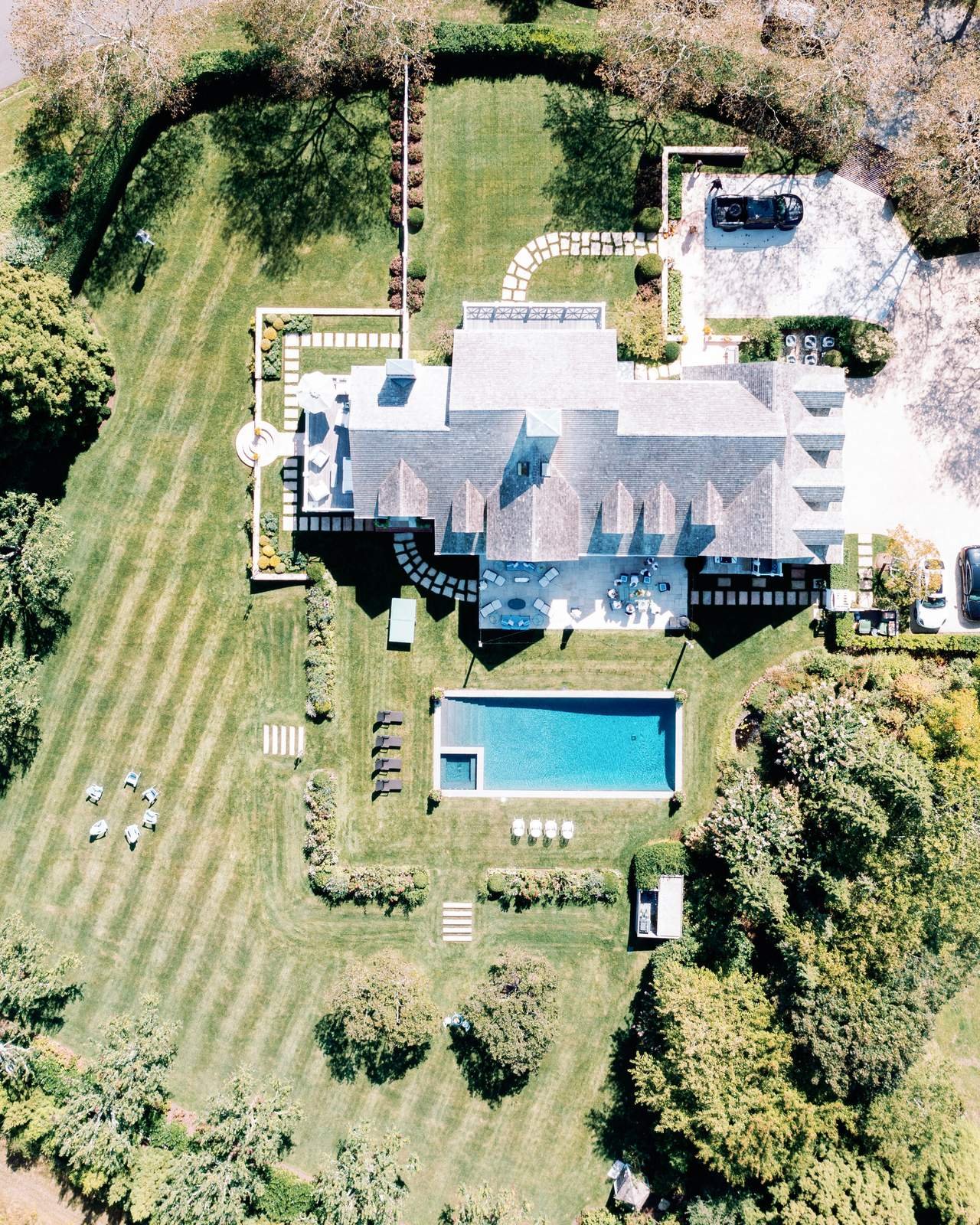 Aerial view of a shingled estate, lawn and pool in East Hampton