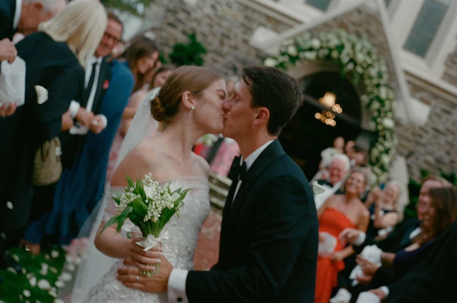 Bride and groom kissing in a shower of petals outside St. Luke's East Hampton