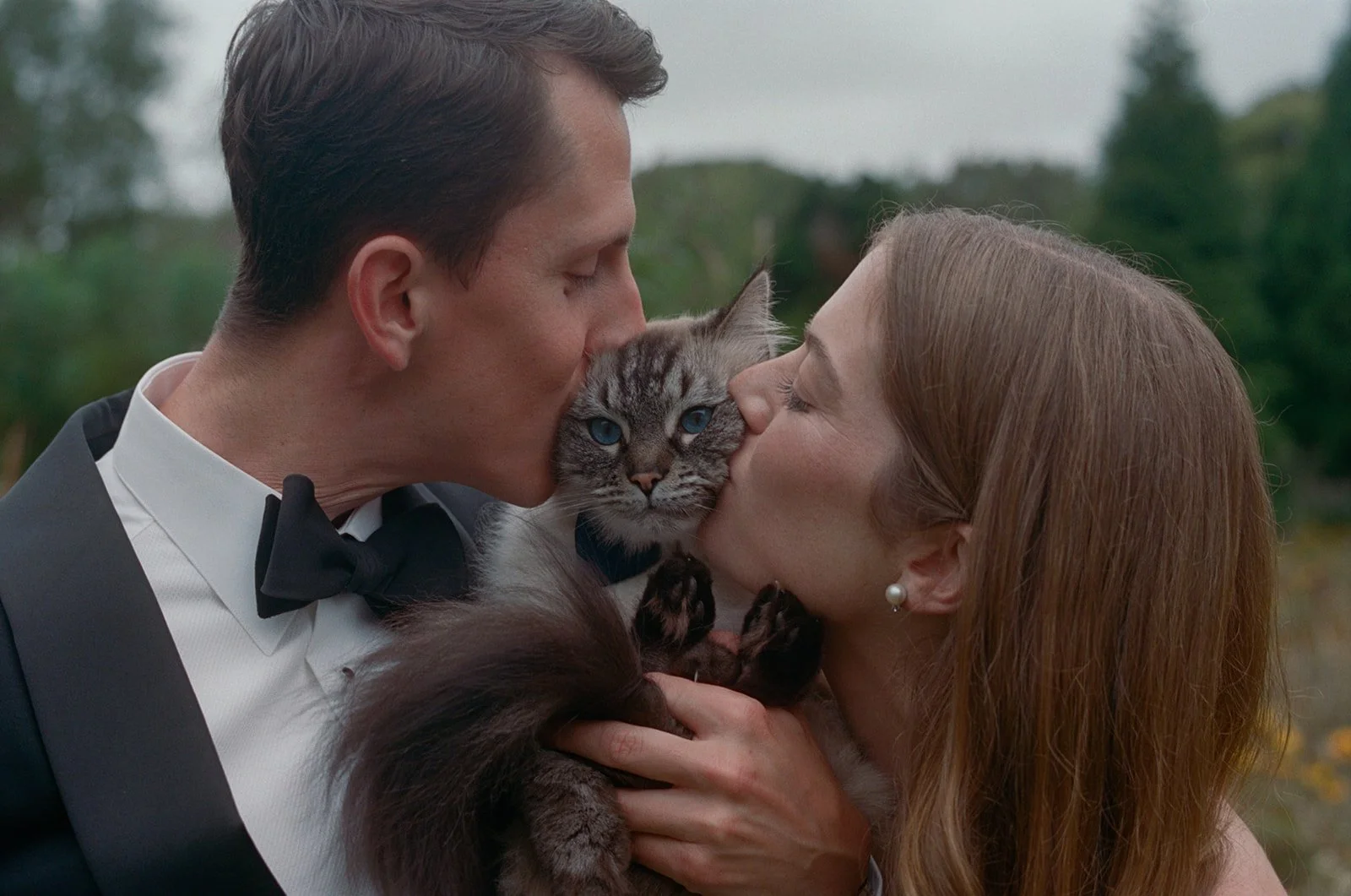 Bride and groom kissing their cat in the garden in East Hampton