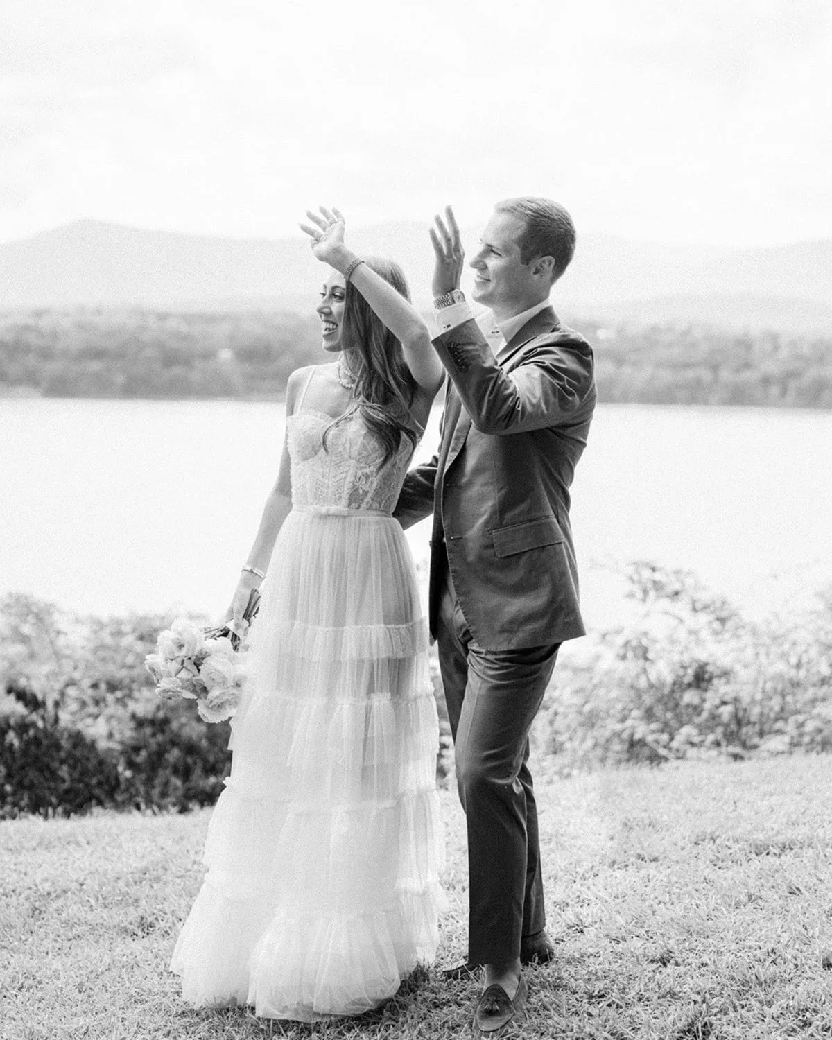 Black and white photo of the bride and groom celebrating on the lawn above the Hudson River at Southwood Estate in Germantown, NY