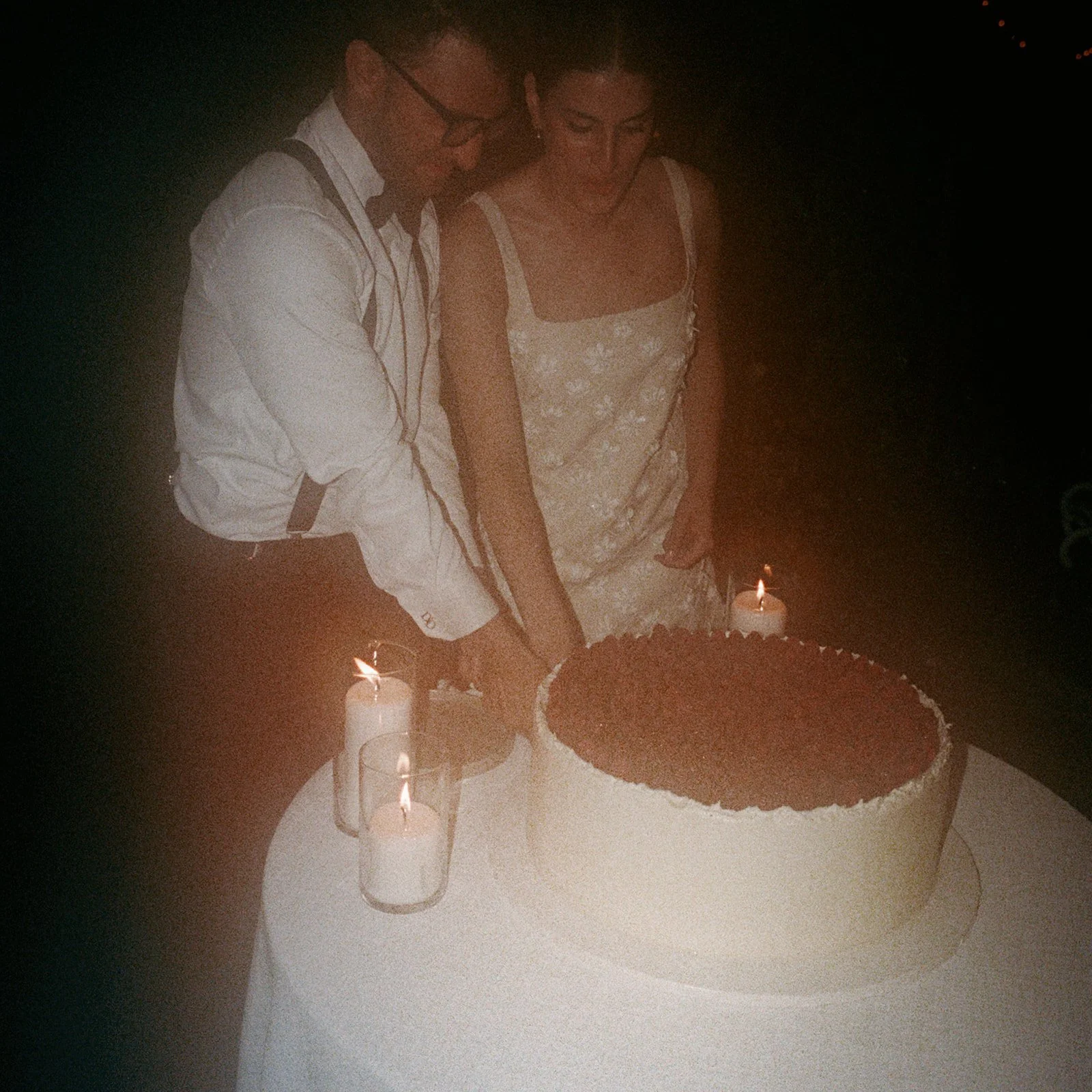 Couple cutting the cake by candlelight late at night at Glynwood