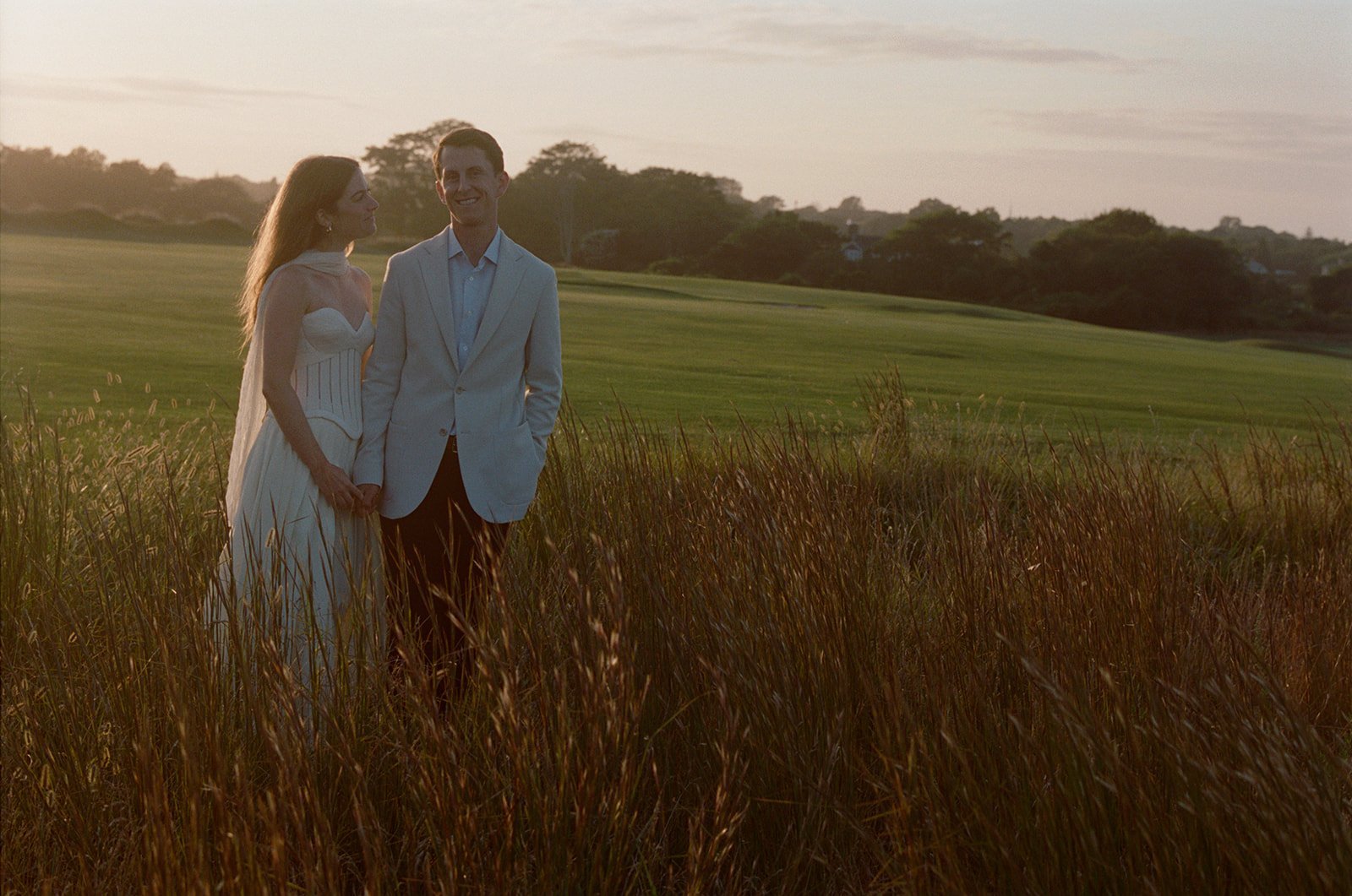 Couple standing in tall grass at golden hour above the golf links in East Hampton