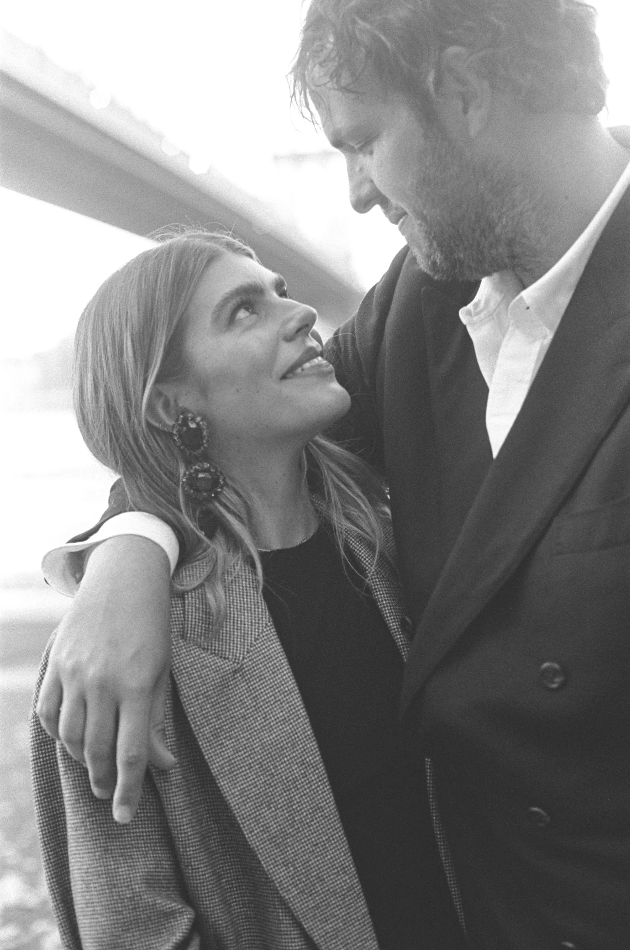 A woman and man in a close, affectionate embrace, gazing into each other's eyes, indoors with natural light.