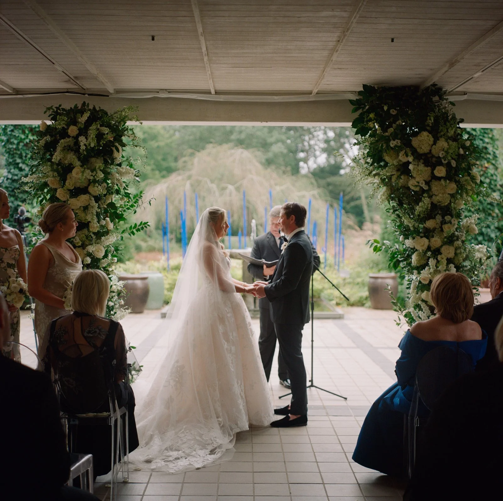 Ceremony on the covered terrace with the gardens and blue glass beyond at LongHouse Reserve
