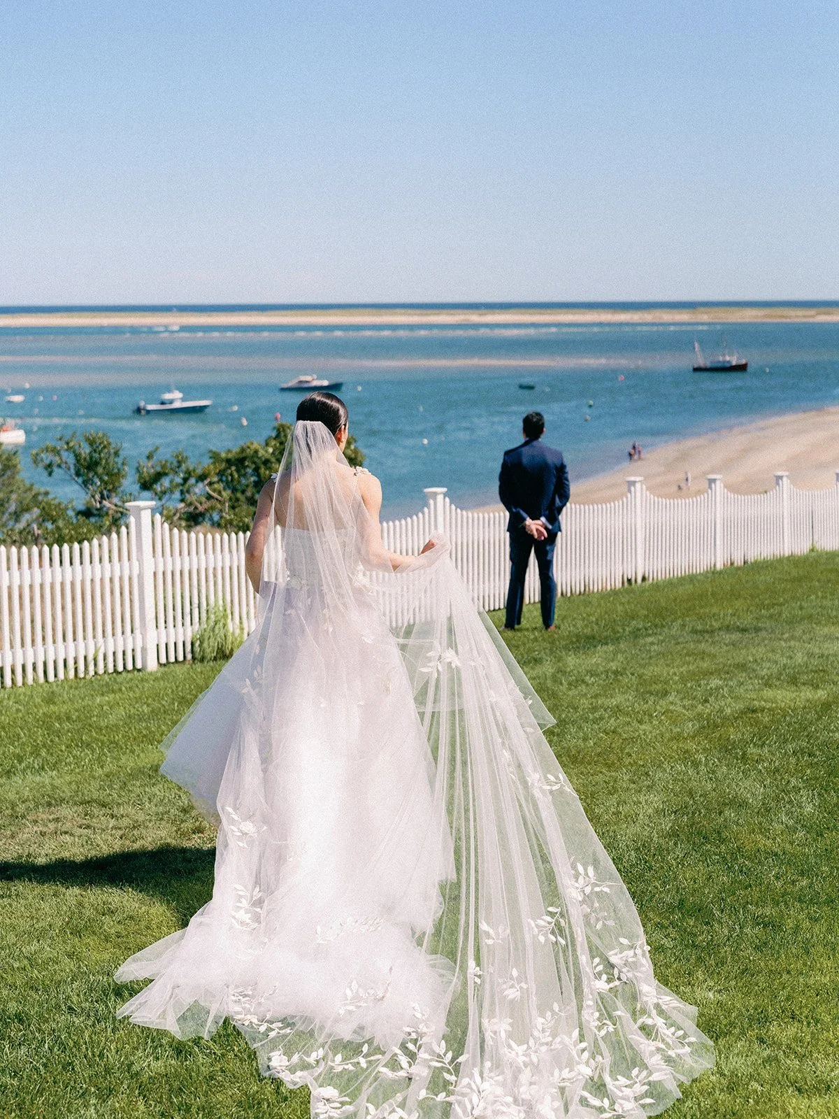 Bride walking across the lawn toward the groom above the harbor at Chatham Bars Inn