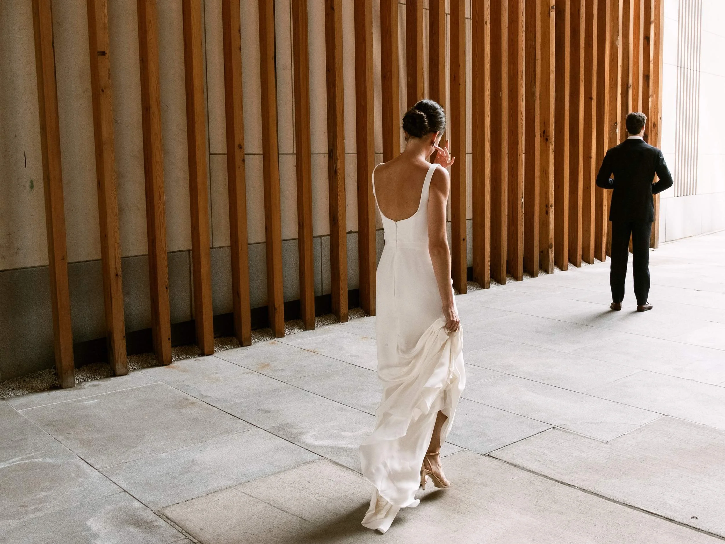 Bride walking toward the groom in the cedar-slatted courtyard at 1 Hotel Brooklyn Bridge