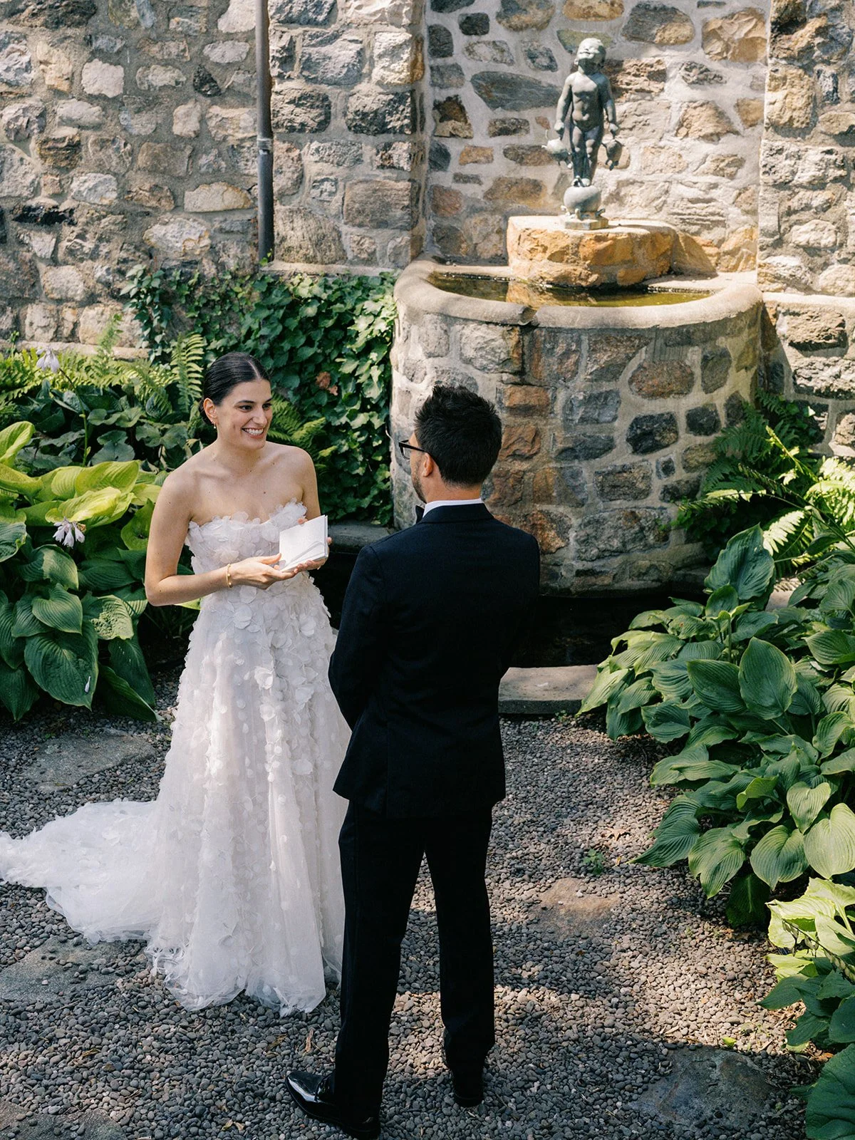 Bride and groom reading private vows by a stone fountain at Glynwood Farm in Cold Spring, NY