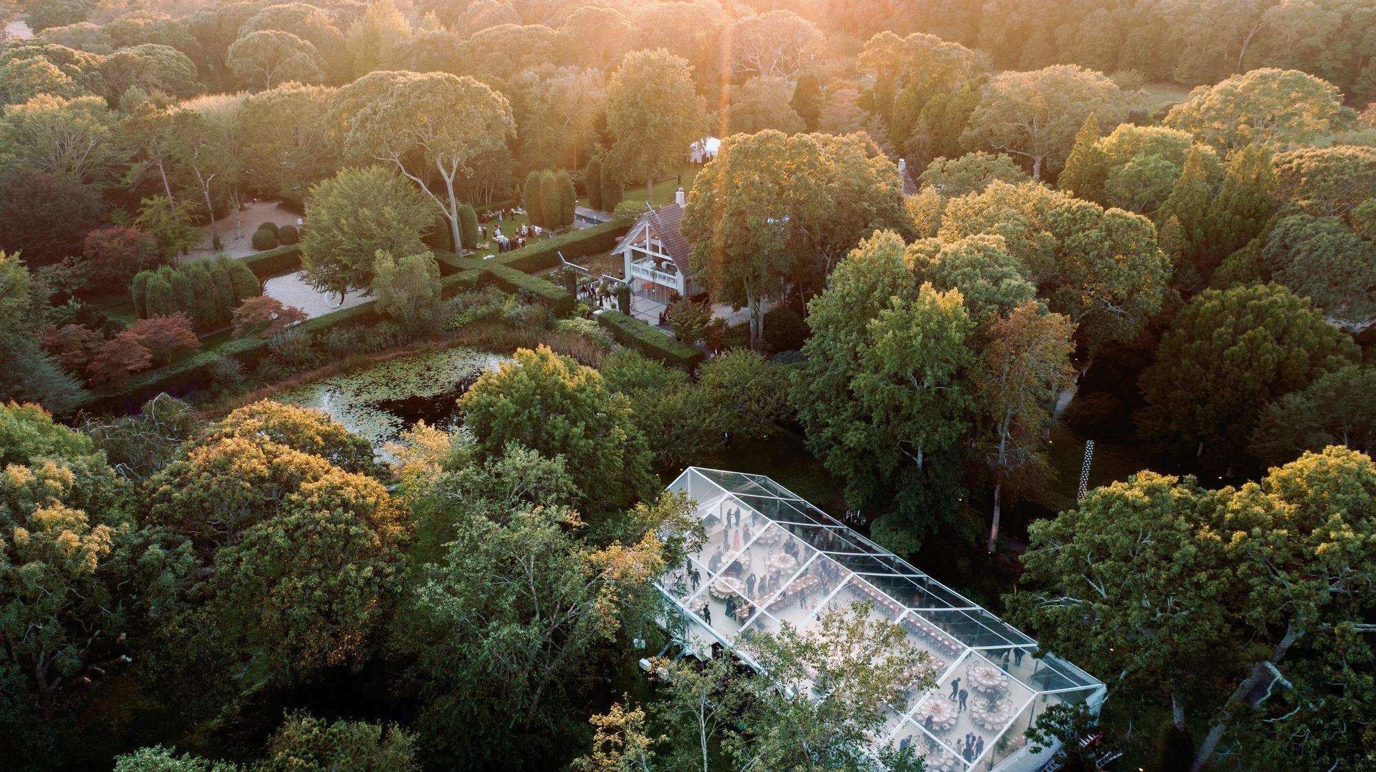 Aerial view at sunset of the clear tent tucked into the trees at LongHouse Reserve